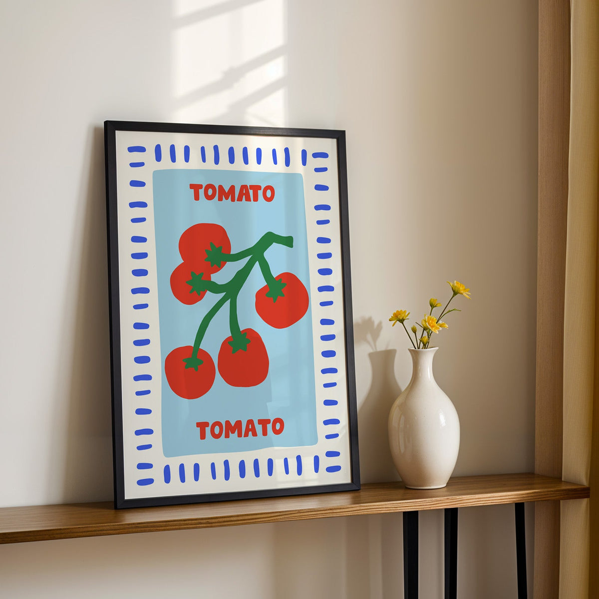 Tomato seed packet print in a black frame on a console table with yellow daisies