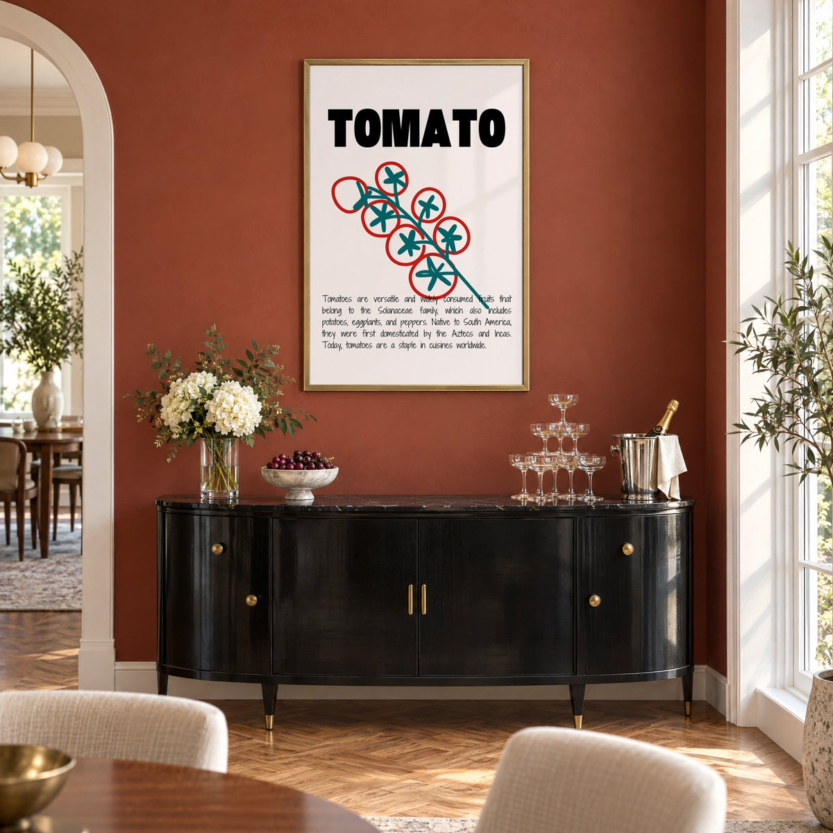 TOMATO bold type tomato vine print in a brass frame on a terracotta wall above a black buffet with a champagne tower