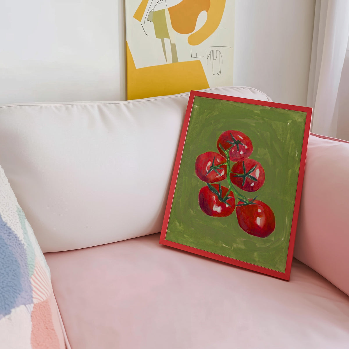 Olive green tomato print shown in a red frame leaning on a blush pink sofa