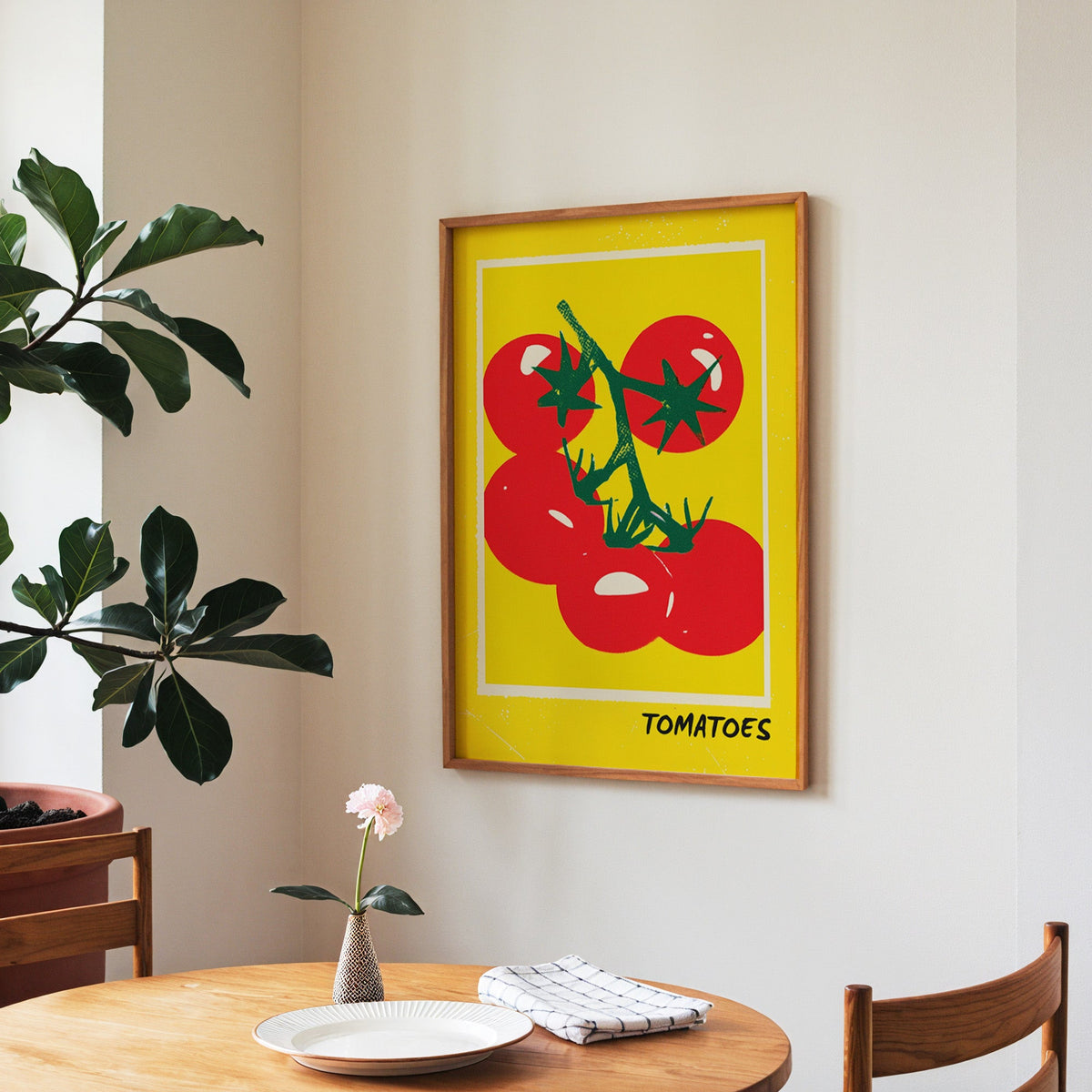 Tomatoes print in a walnut frame above a round table beside a fiddle-leaf fig