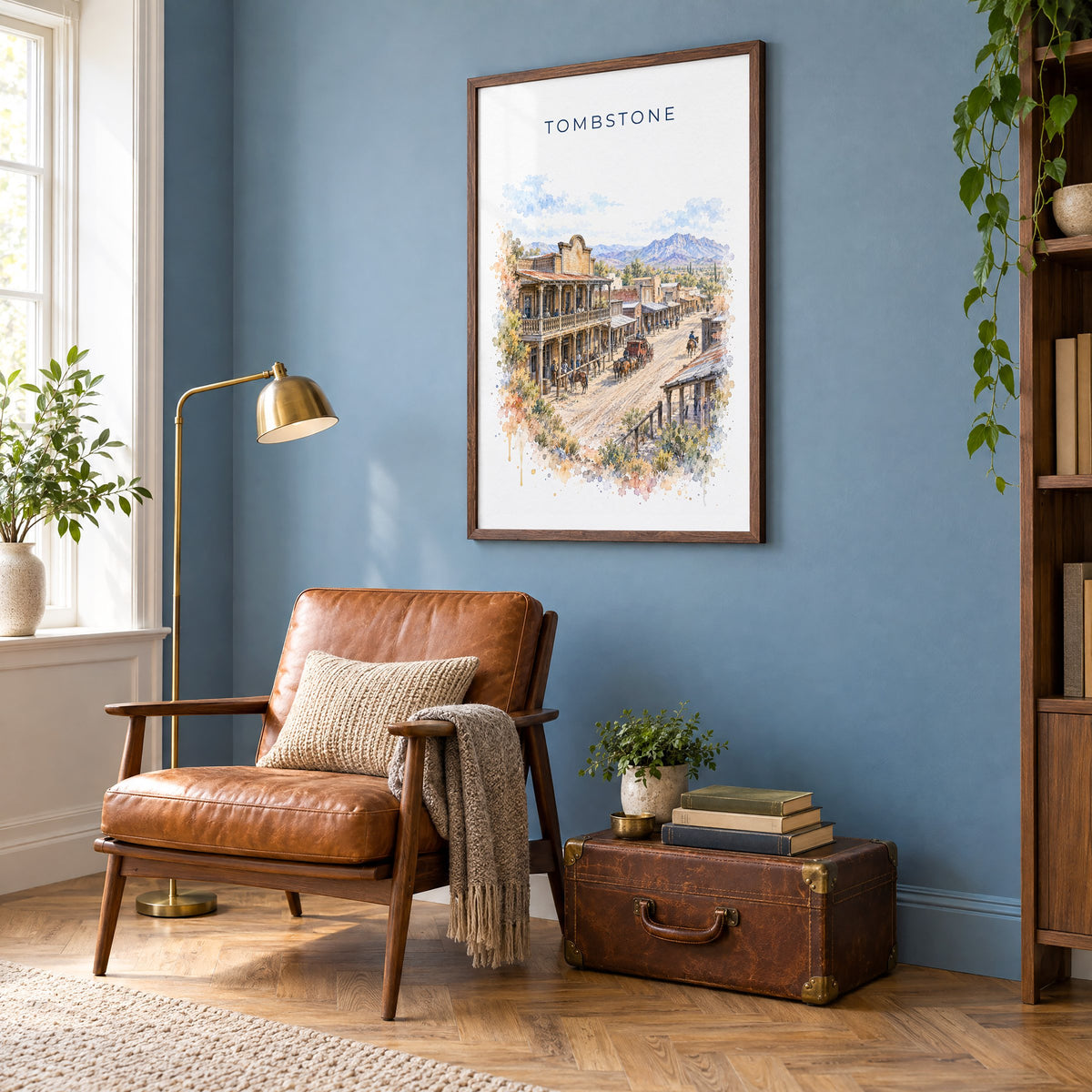 Tombstone, Arizona watercolor print in a walnut frame on a blue wall above a leather armchair in a reading nook