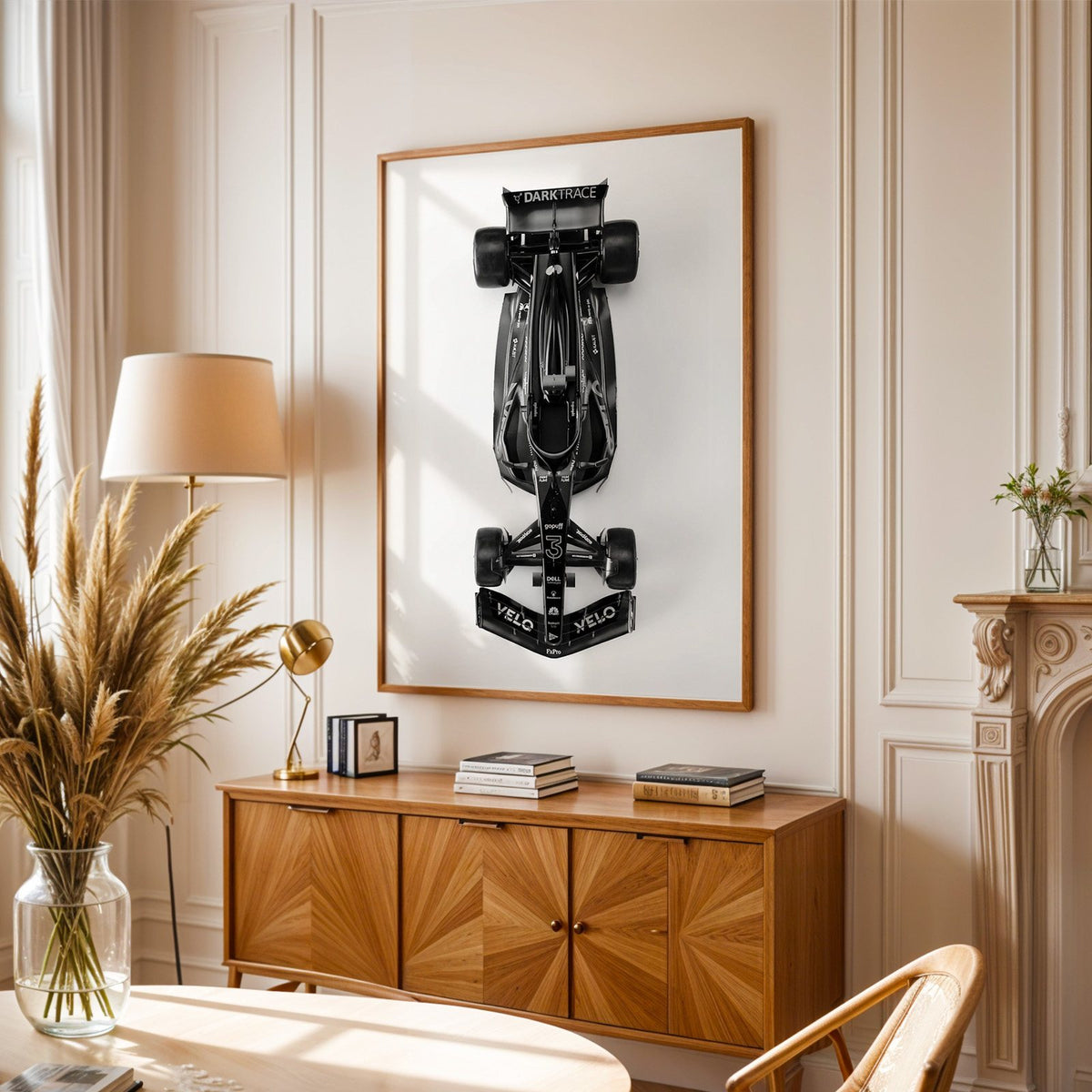 Top view black formula-style race car print in an oak frame above a sunburst wood sideboard with pampas grass