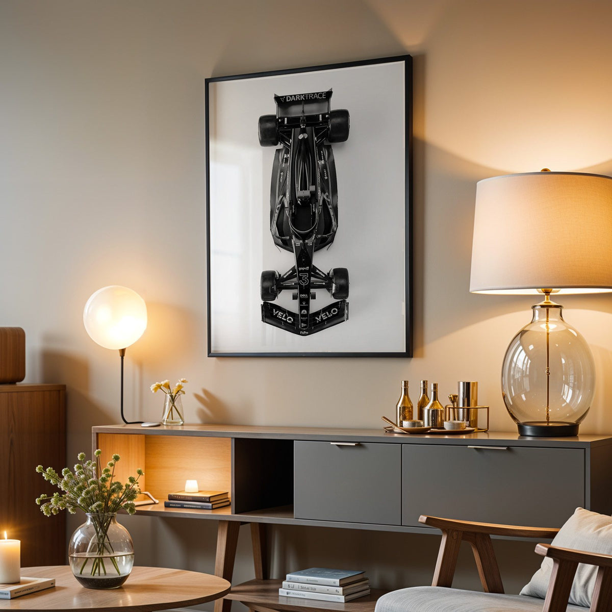 Top view black formula-style race car print in a black frame above a grey media console with a glass table lamp