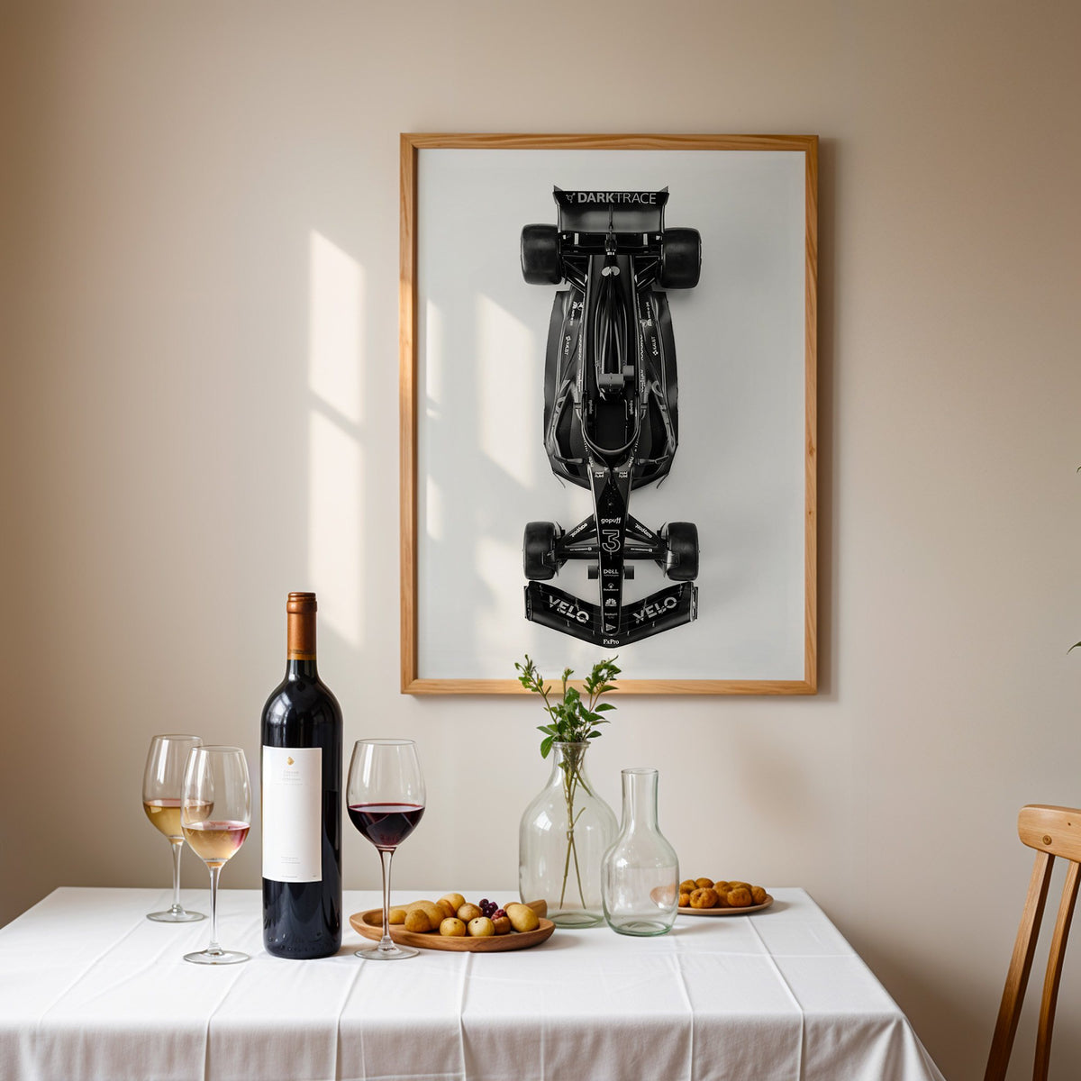Top view black formula-style race car print in an oak frame above a table set with red wine and glasses