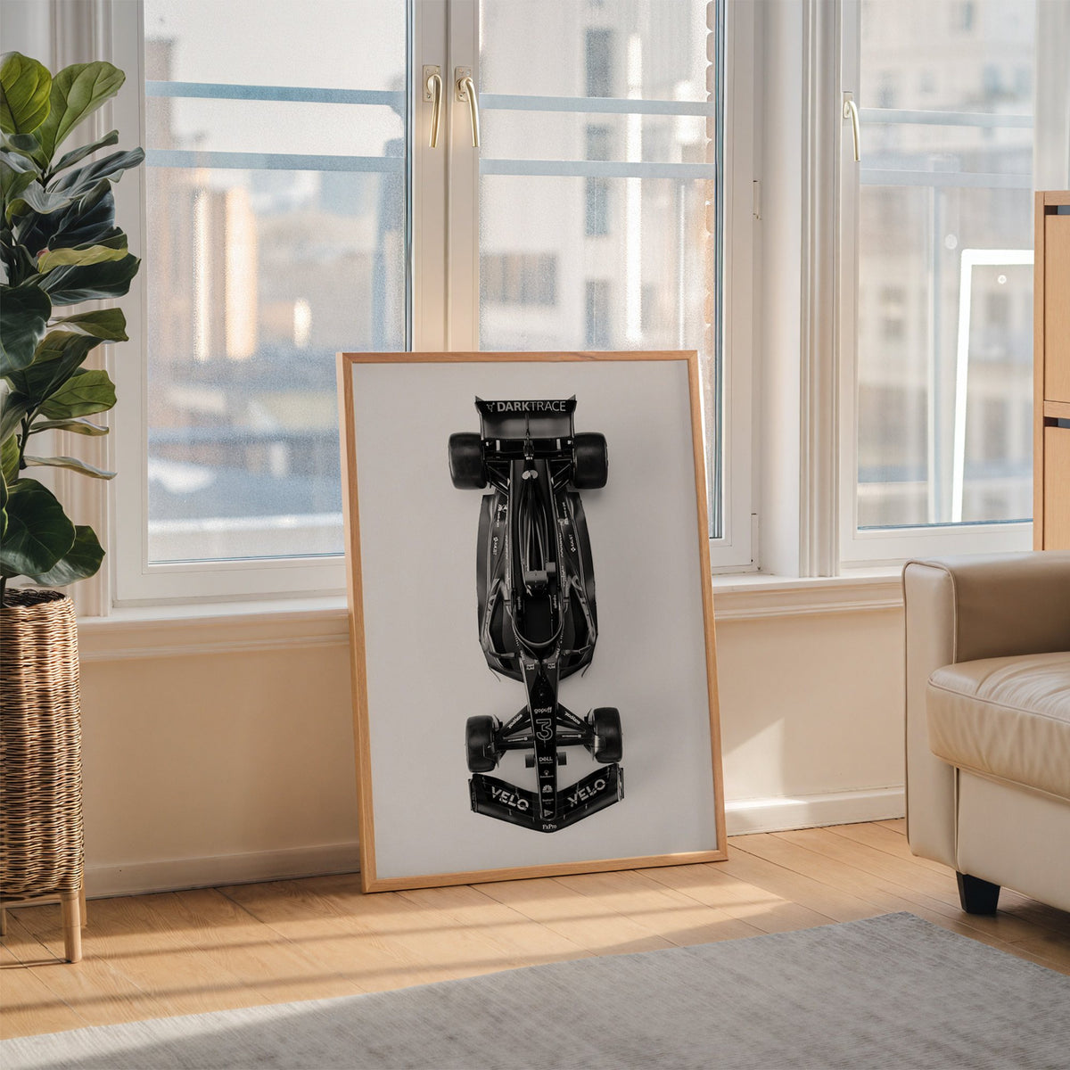 Top view black formula-style race car print in an oak frame leaning on the floor beside a fiddle leaf fig