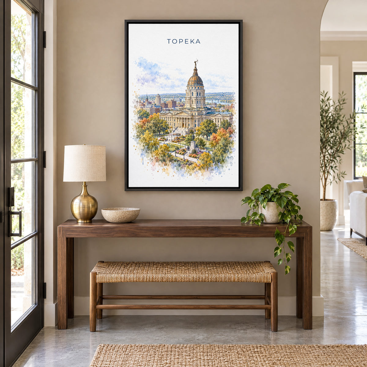 Topeka watercolor print as a black floater canvas above a walnut console and woven bench in an entryway
