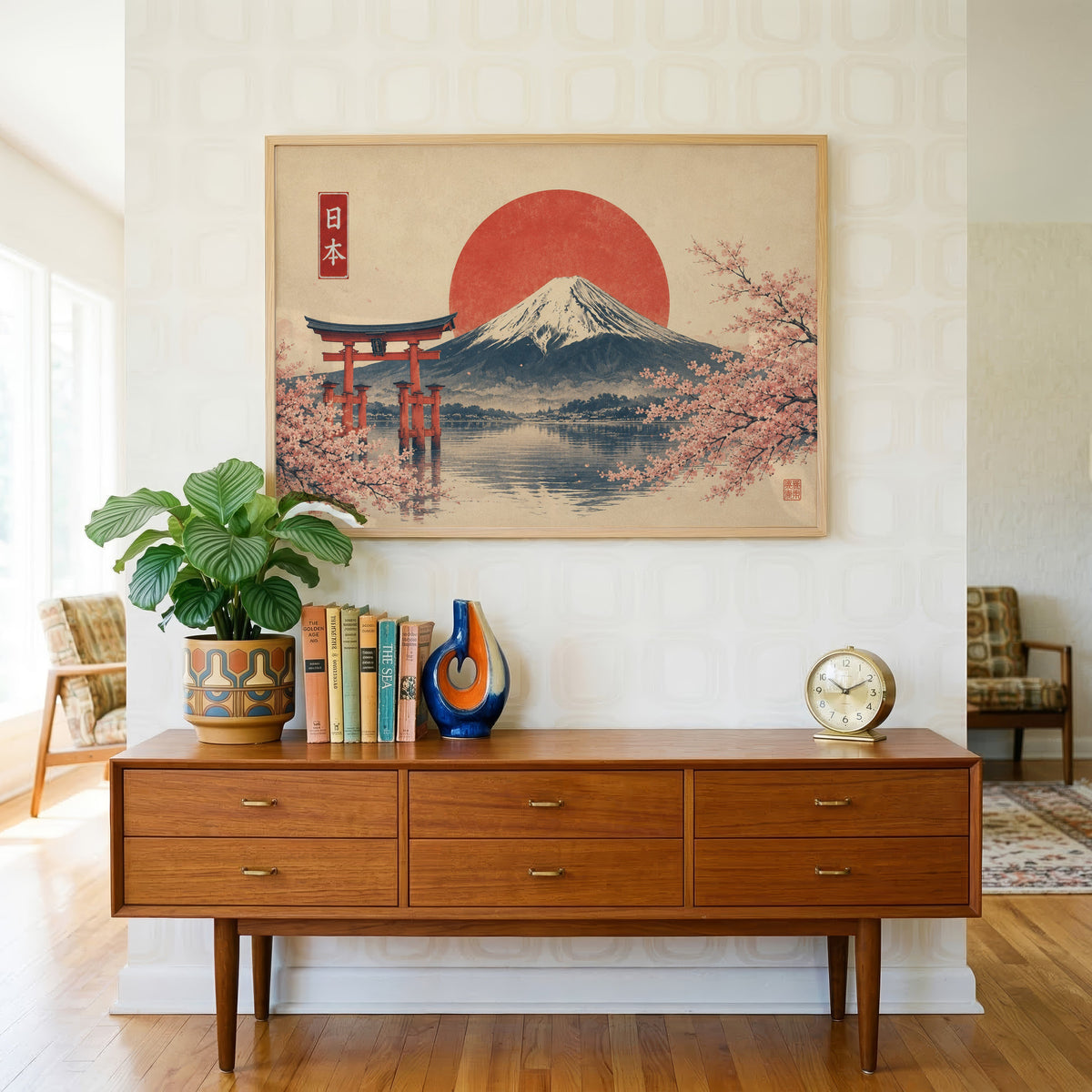 Torii gate and Mount Fuji with sakura print in a light oak frame above a teak credenza with books and a brass clock