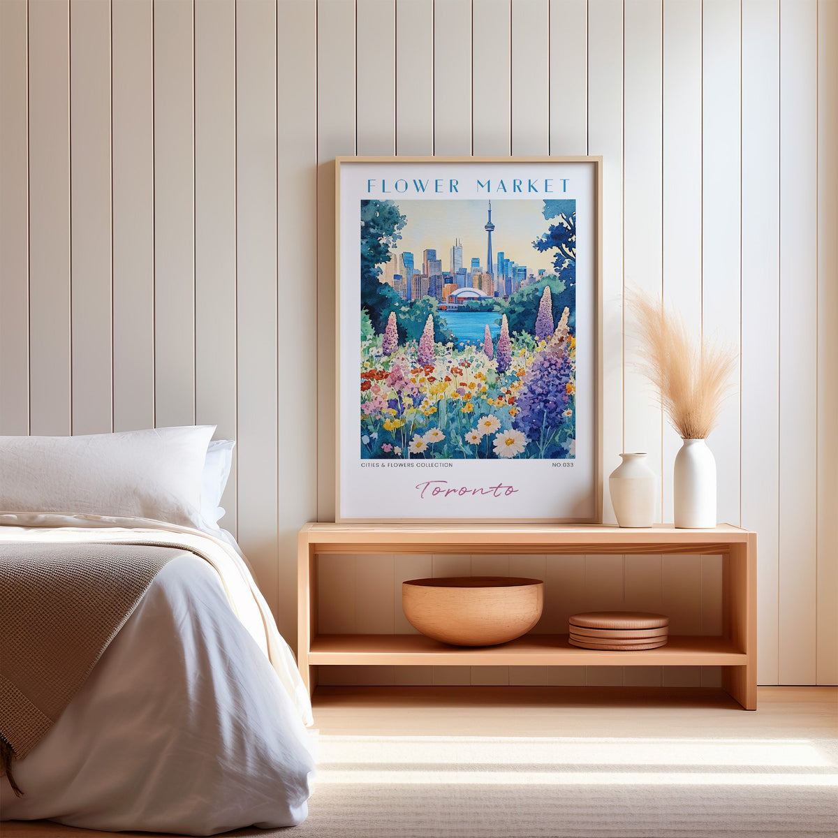 Toronto flower market print in an oak frame on a wood bench against a white shiplap bedroom wall with pampas grass