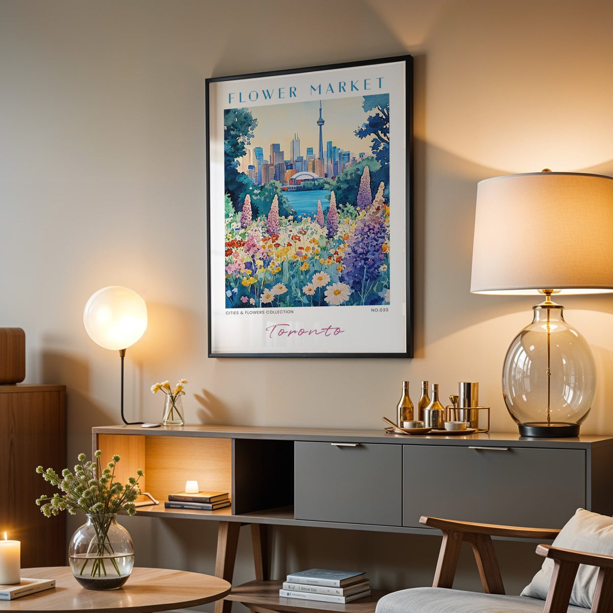 Toronto flower market print in a black frame above a grey media console with a glass table lamp