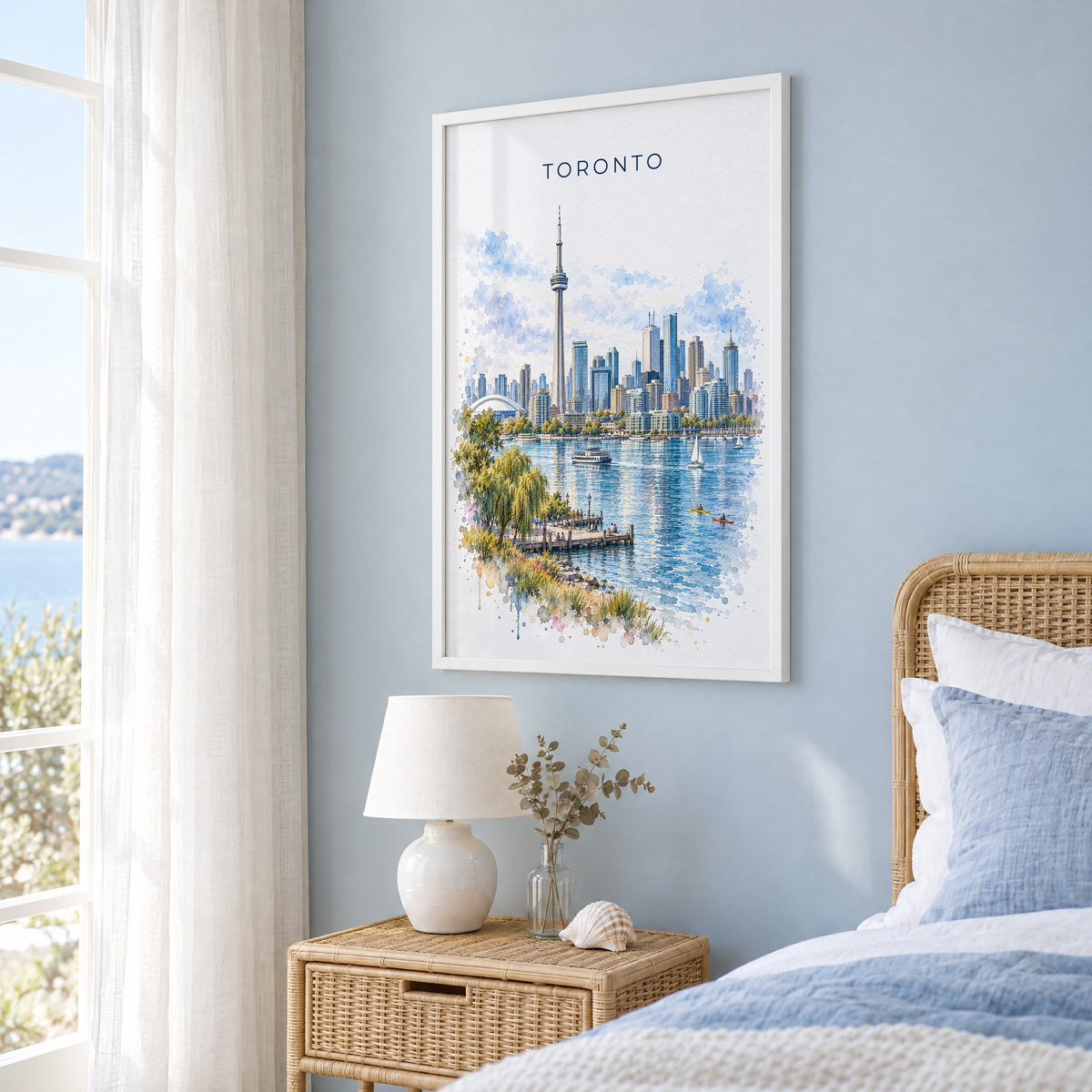 Toronto watercolor print in a white frame on a pale blue wall beside a rattan bed in a coastal bedroom