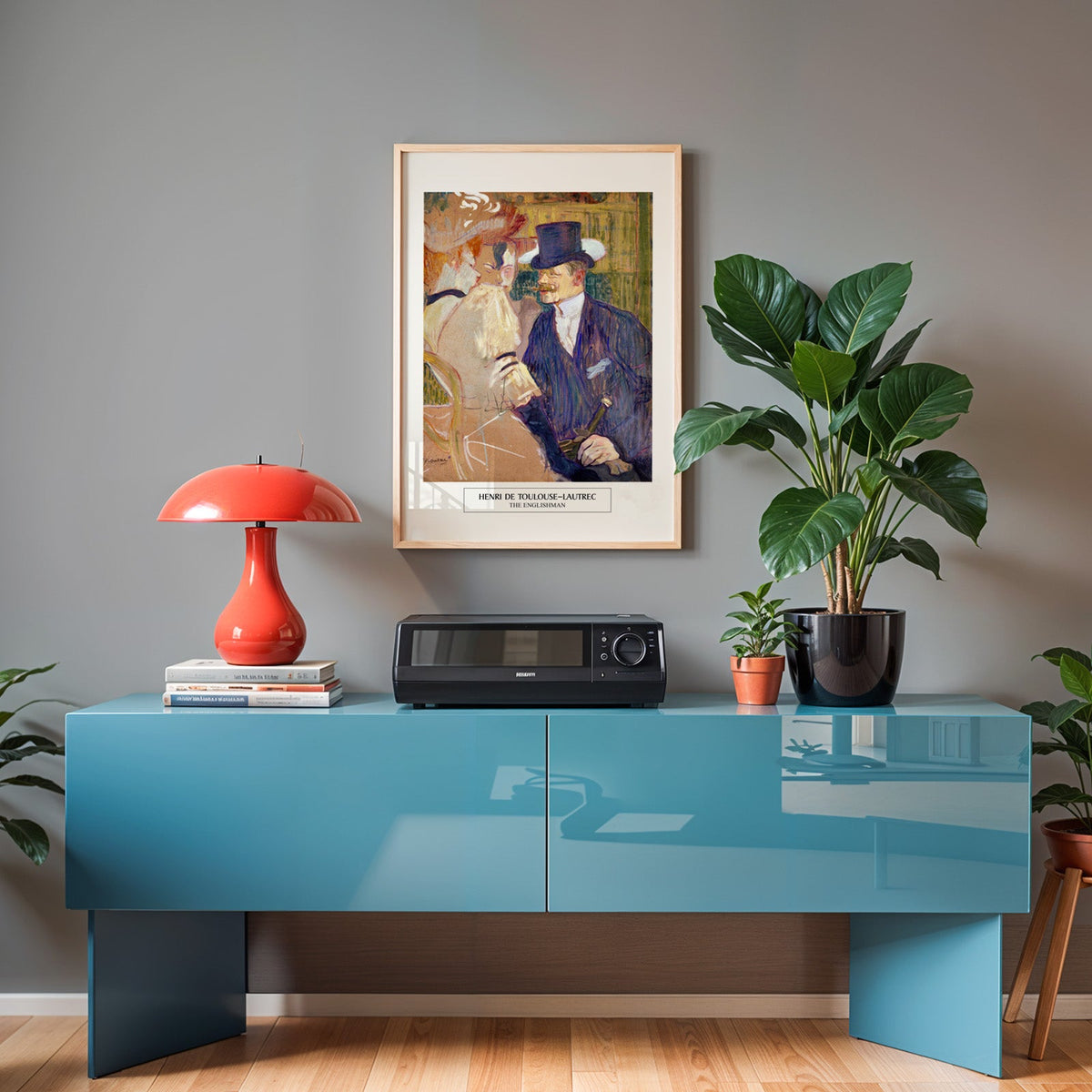 Lautrec print in an oak frame above a teal sideboard with a red lamp