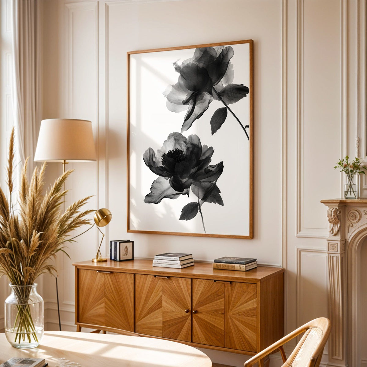 Two translucent X-ray flowers on white print in an oak frame above a sunburst wood sideboard with pampas grass