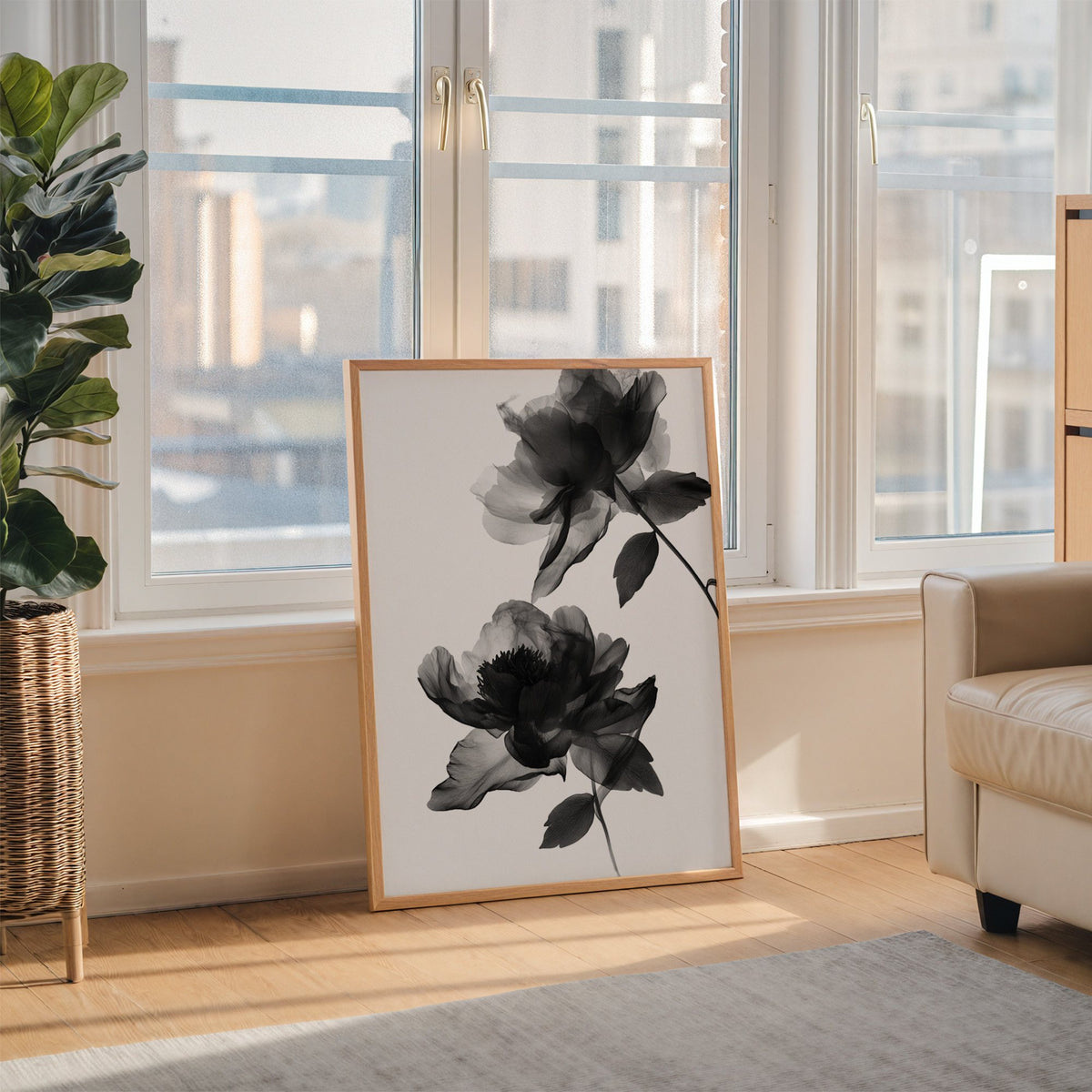 Two translucent X-ray flowers on white print in an oak frame leaning on the floor beside a fiddle leaf fig