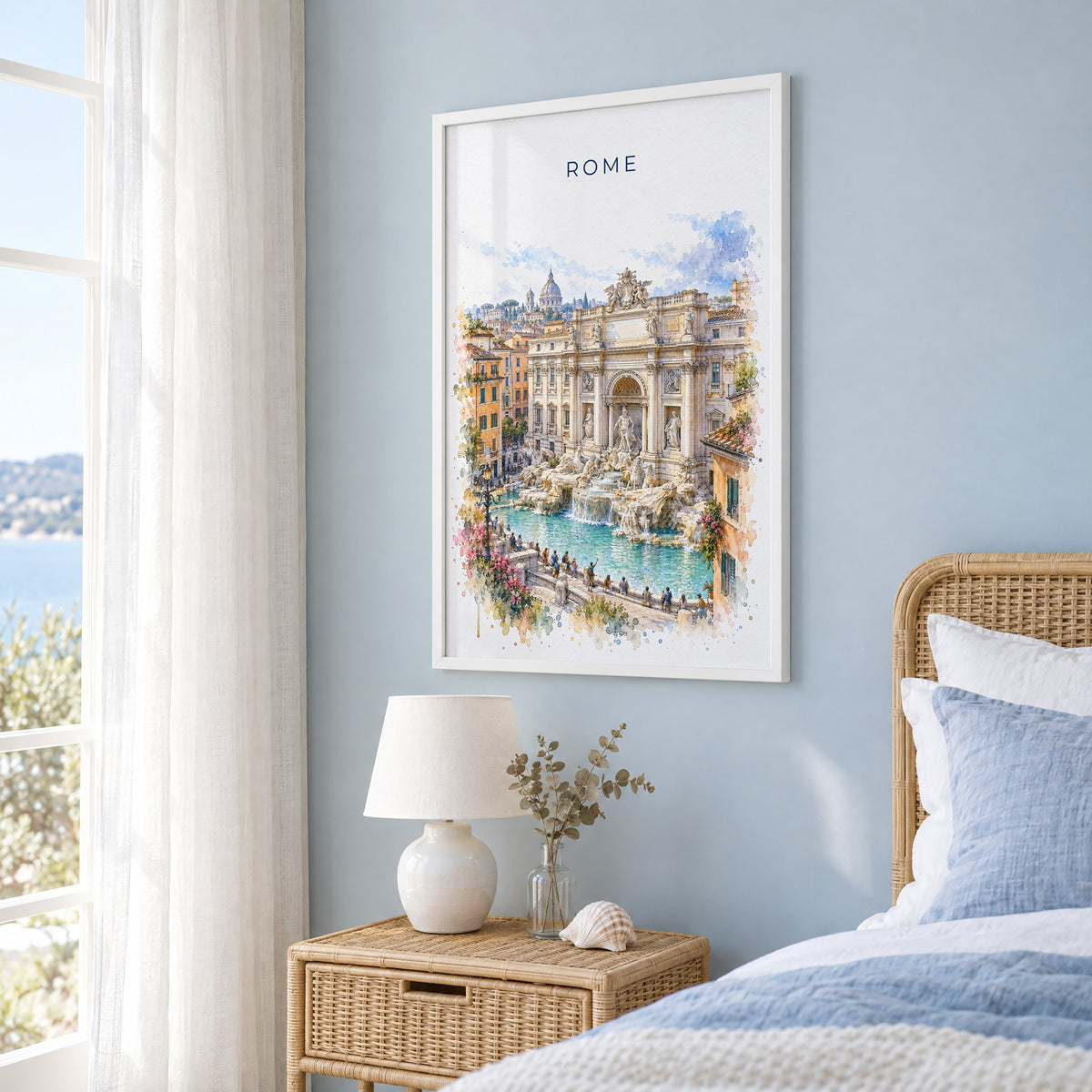 Trevi Fountain watercolor print in a white frame on a pale blue wall beside a rattan bed in a coastal bedroom