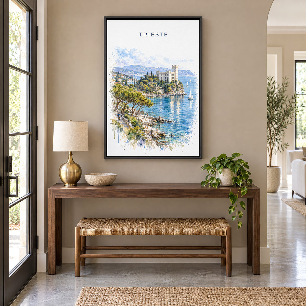 Trieste watercolor print as a black floater canvas above a walnut console and woven bench in an entryway