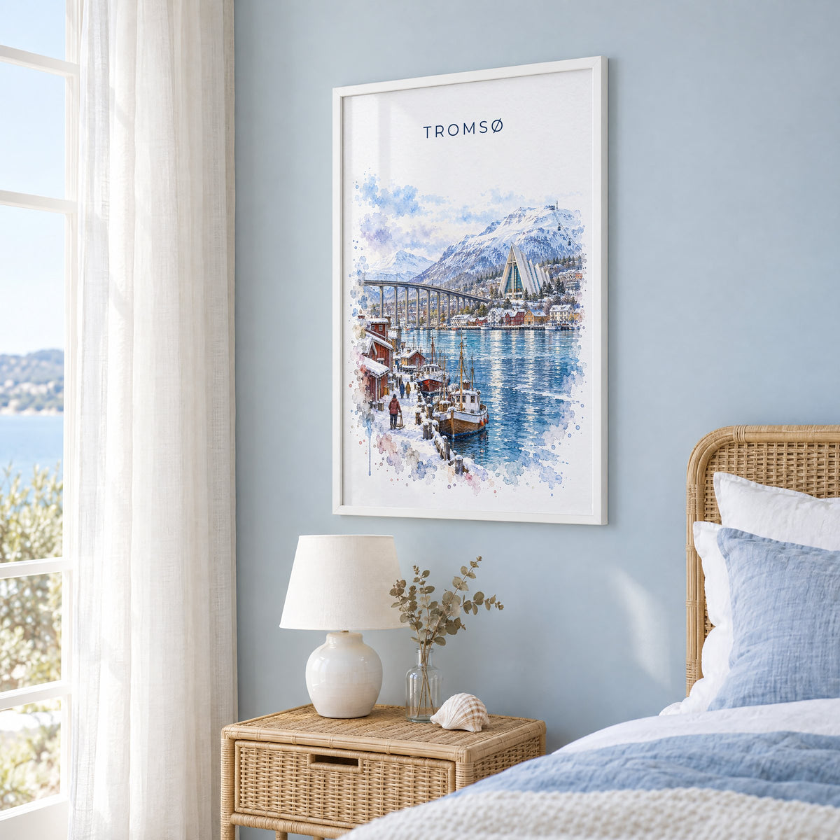 Tromsø, Norway watercolor print in a white frame on a pale blue wall beside a rattan bed in a coastal bedroom