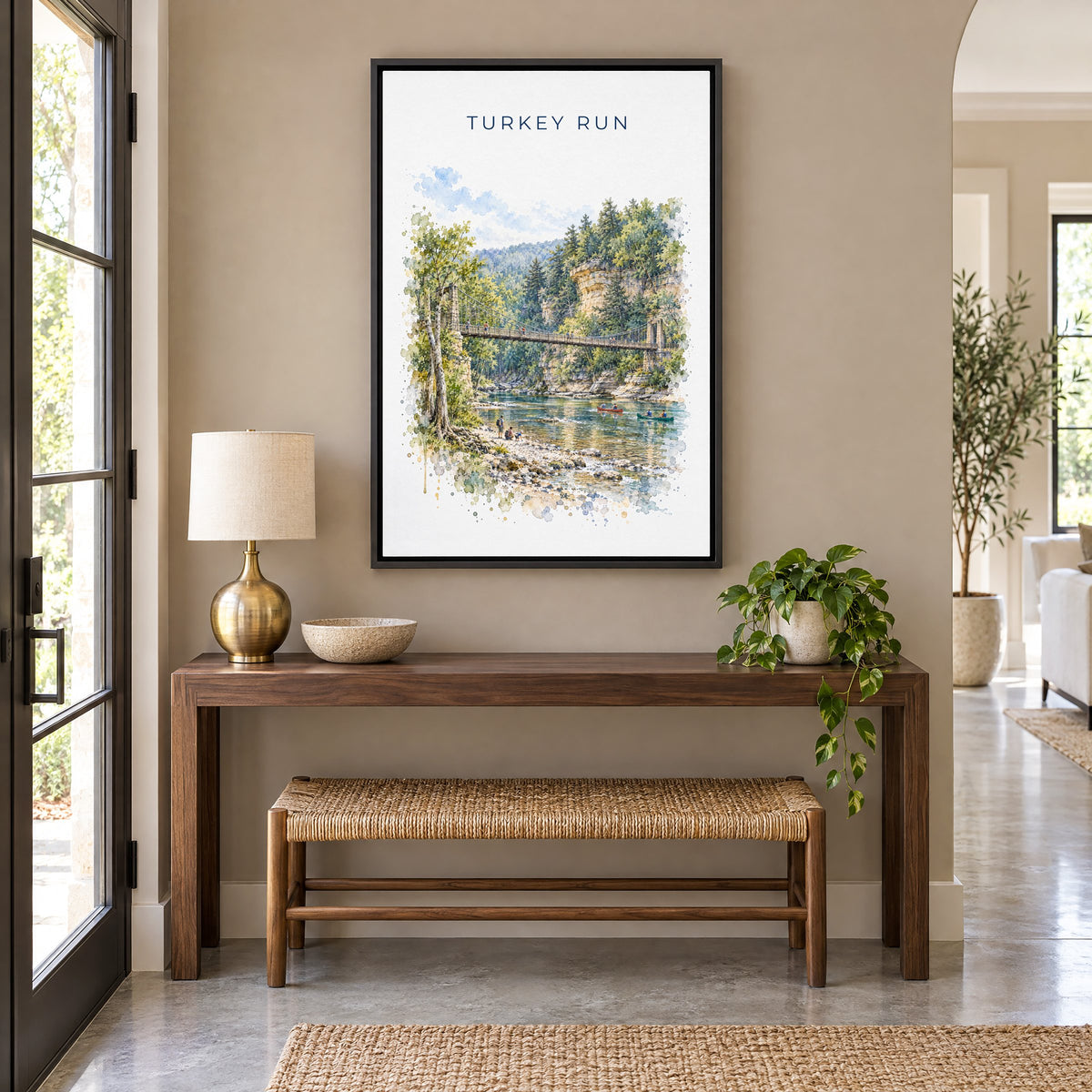 Turkey Run State Park watercolor print as a black floater canvas above a walnut console and woven bench in an entryway