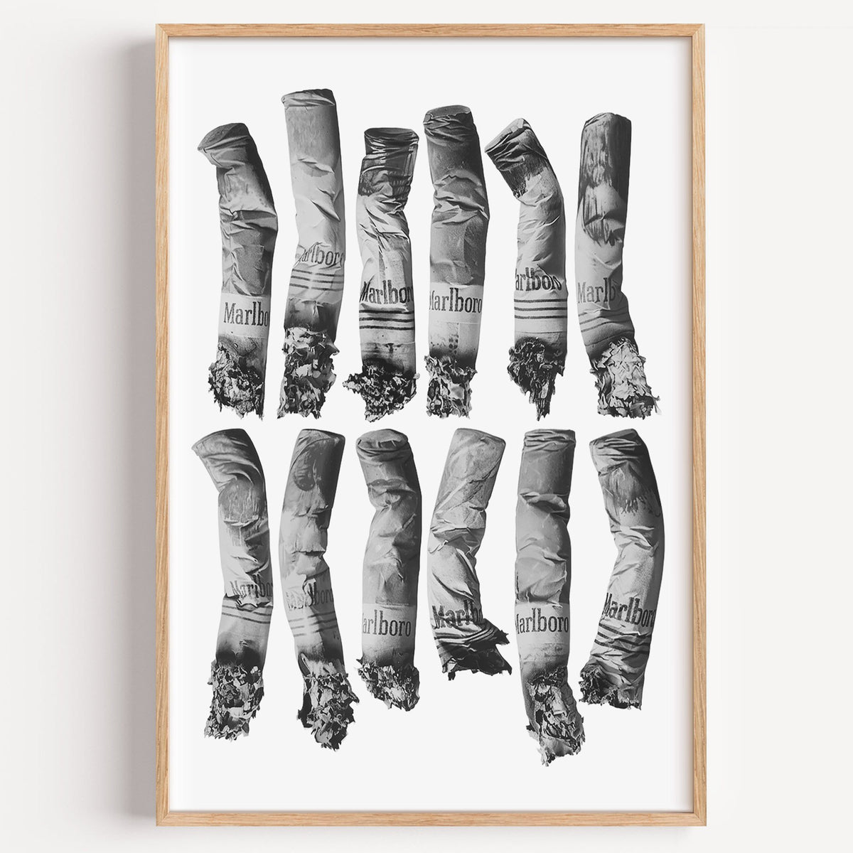 Twelve crushed cigarette ends in two rows print in a light oak frame on a plain white wall