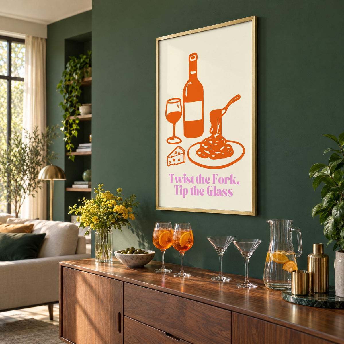 Twist the Fork, Tip the Glass wine and pasta print in a brass frame on a bottle green wall above a sideboard with spritz and martini glasses, seen at an angle