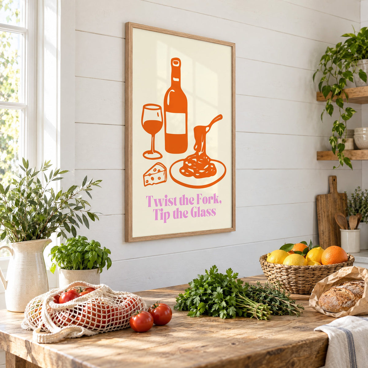 Twist the Fork, Tip the Glass wine and pasta print in an oak frame on a shiplap wall above a farm table with market tomatoes and citrus, seen at an angle