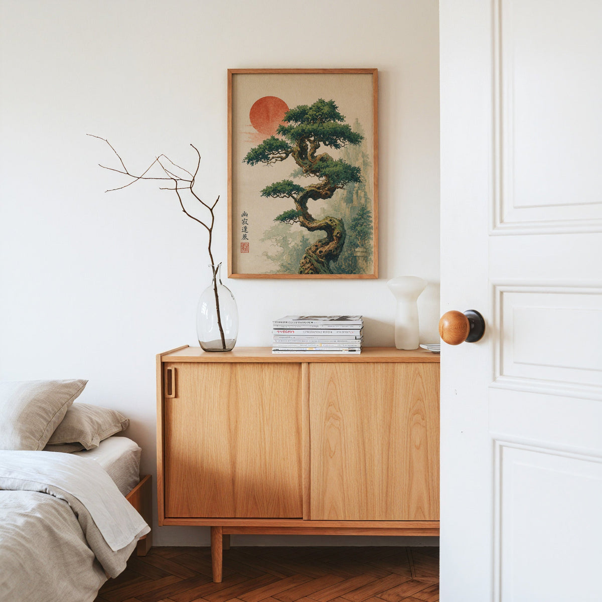 twisted bonsai tree with red sun print in an oak frame above an oak sideboard in a bedroom with linen bedding