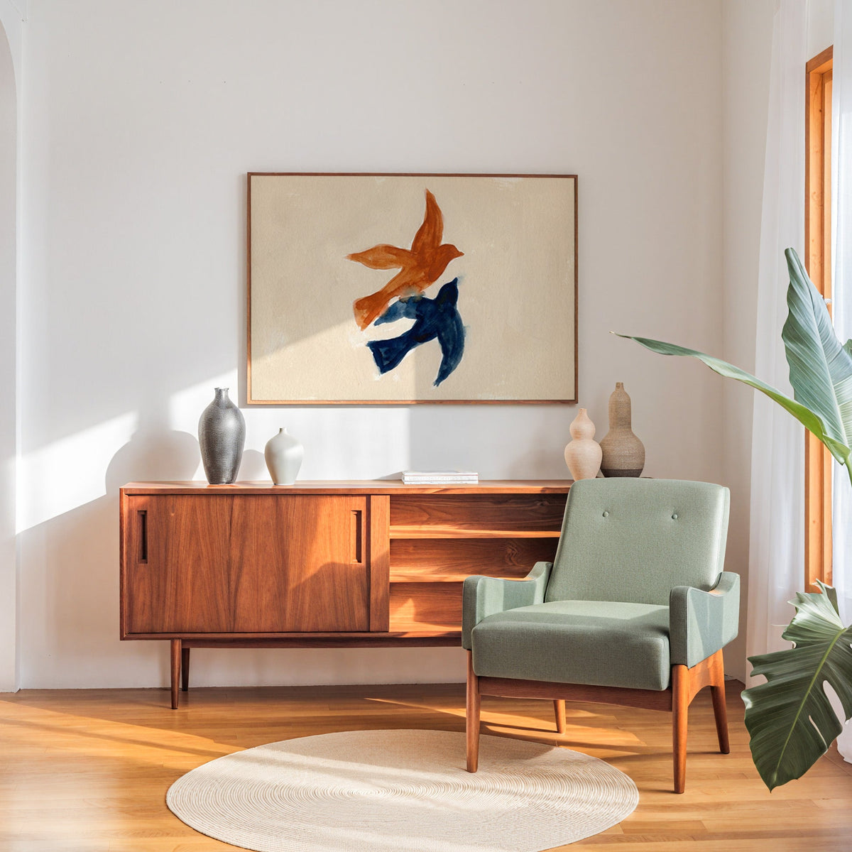 Couple birds watercolor print in a walnut frame above a sideboard beside a sage armchair