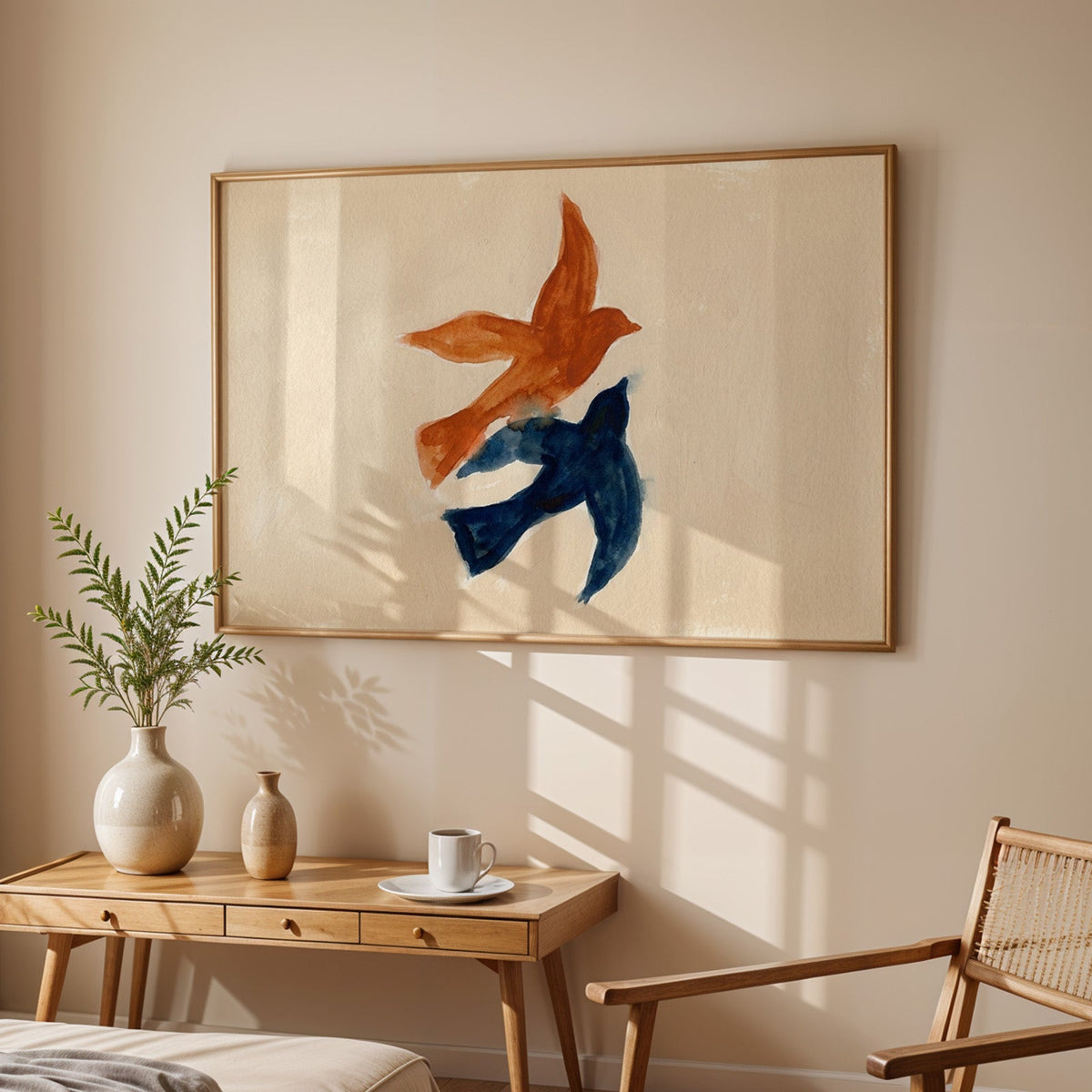 Watercolor birds wall art print in an oak frame above a sunlit desk with a cane chair