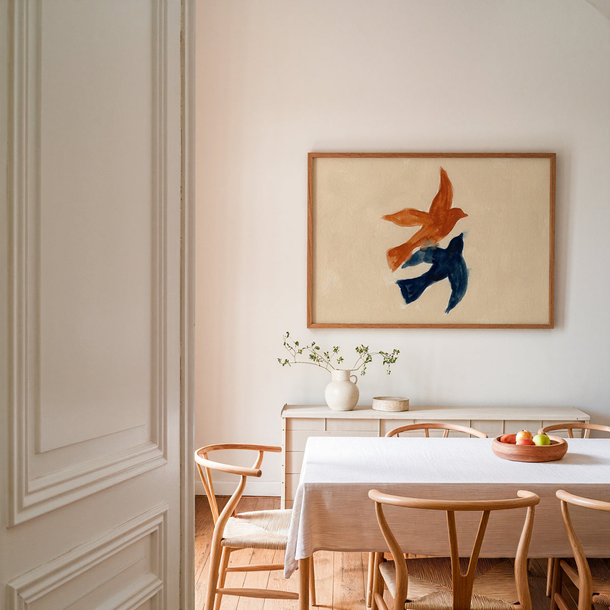 Birds in flight print in an oak frame in a dining room with wishbone chairs