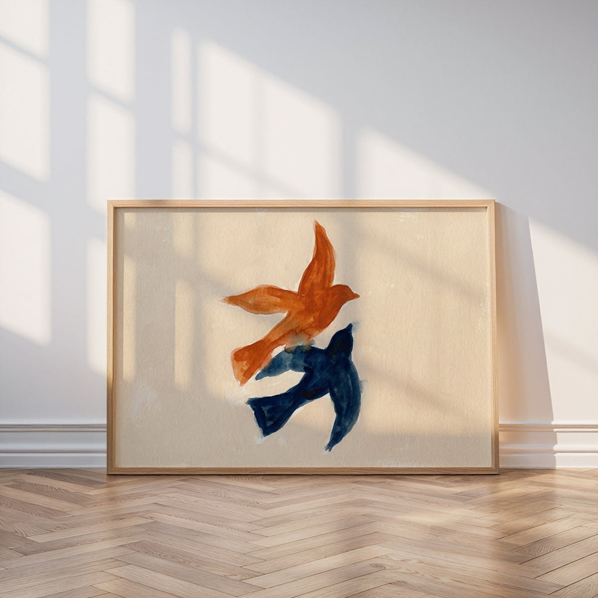 Couple birds watercolor print in an oak frame leaning on a parquet floor in window light