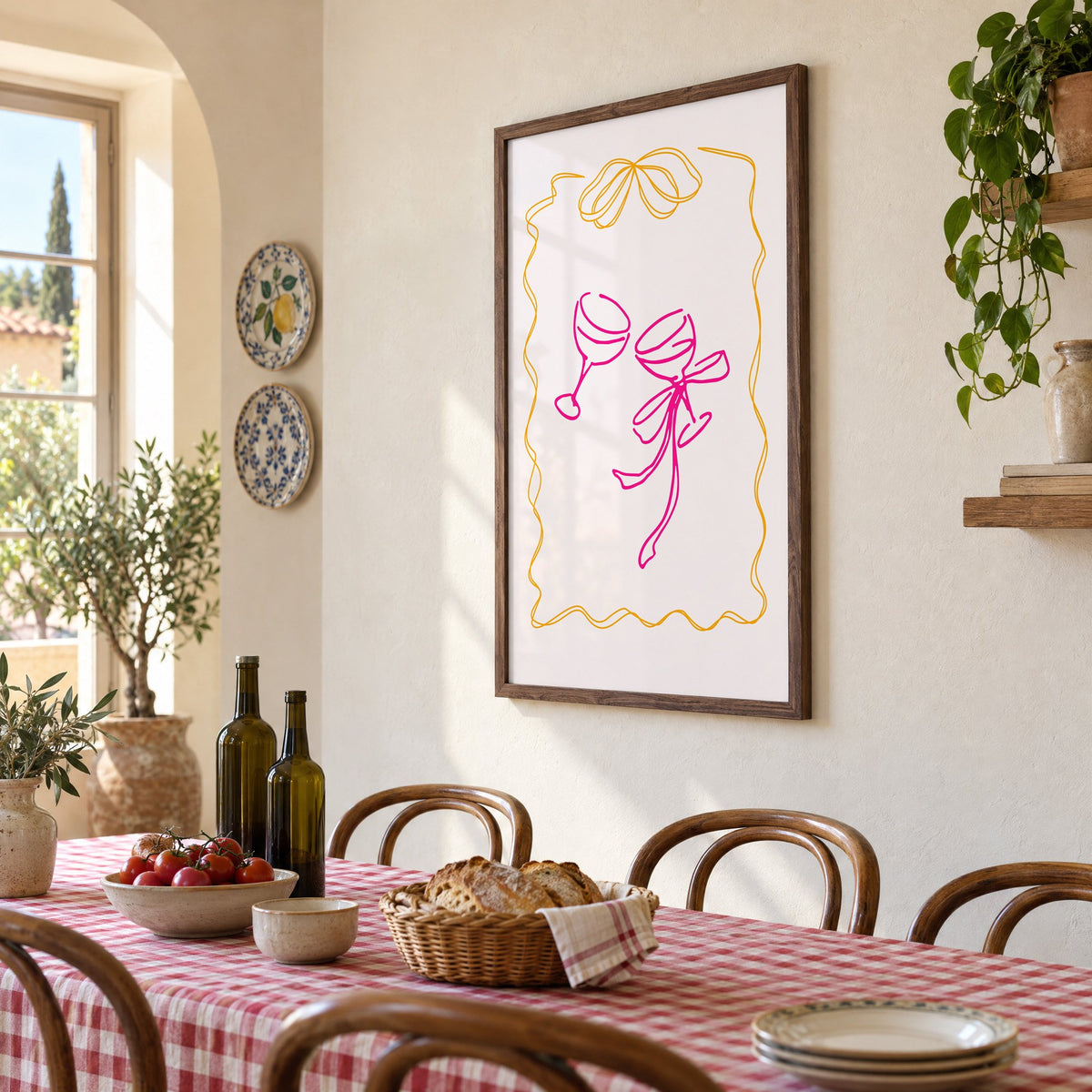 Two coupes pink bow ribbon frame print in a walnut frame above a gingham-covered trattoria table, seen at an angle