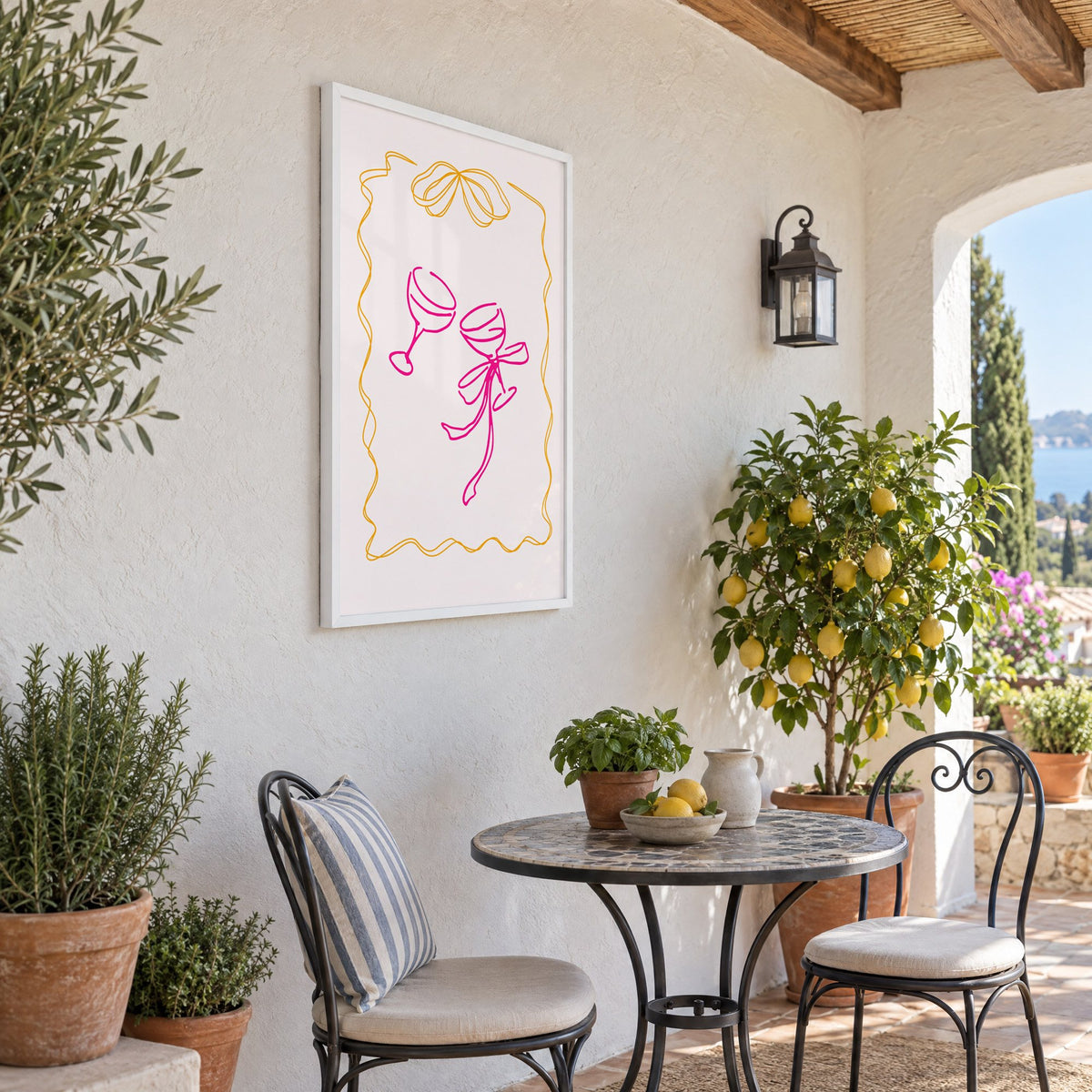 Two coupes pink bow ribbon frame print in a white frame on a sunny patio wall beside a potted lemon tree