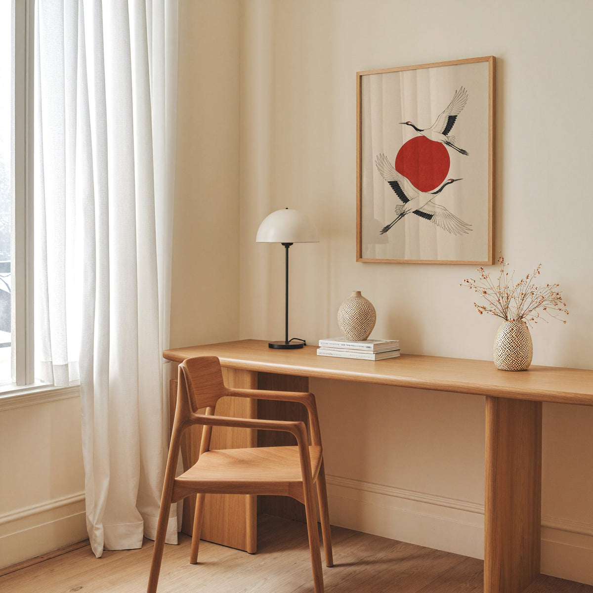 two cranes crossing a red sun print in an oak frame above a long oak desk with a white dome lamp and woven vases