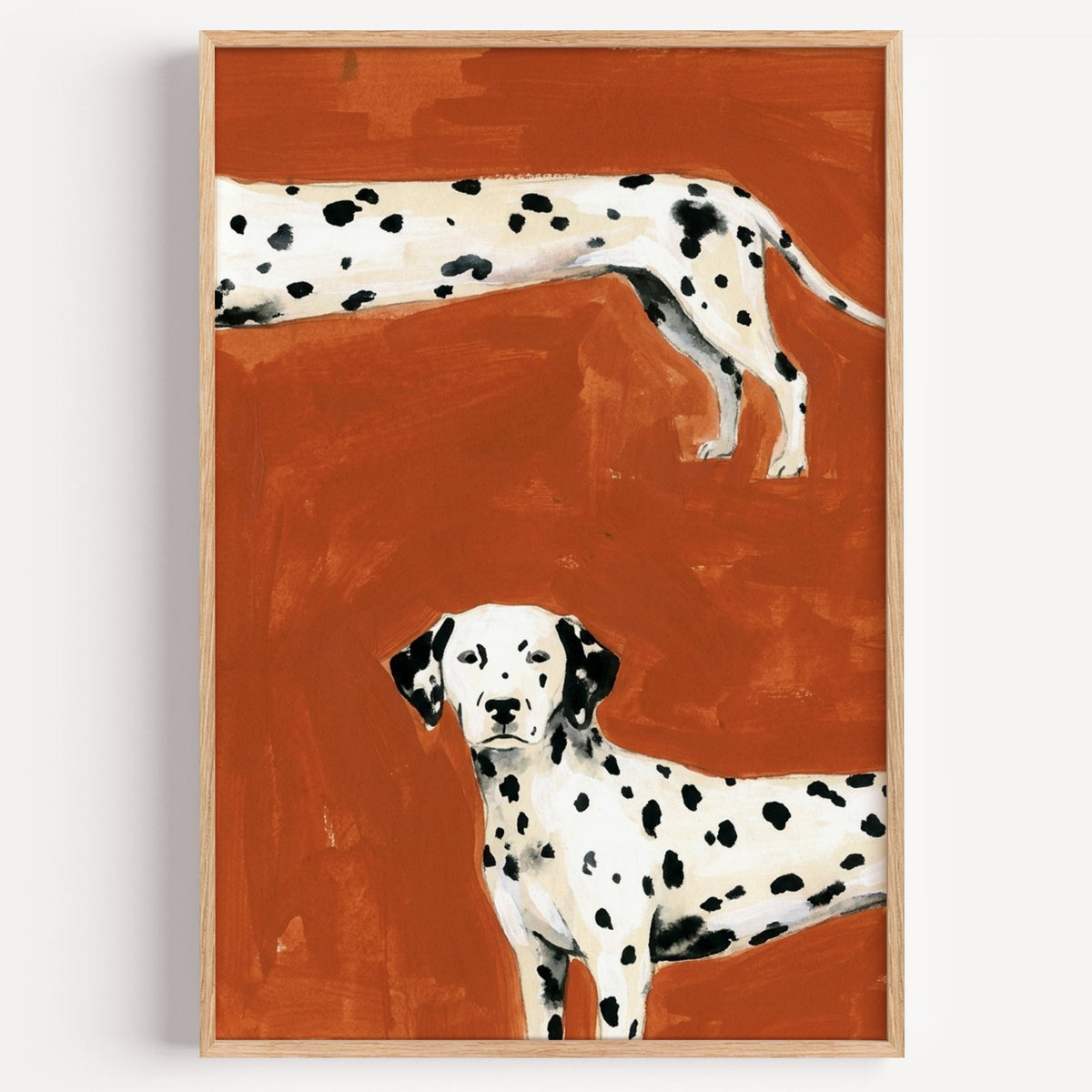 Two Dalmatians print in a light oak frame on a plain white wall