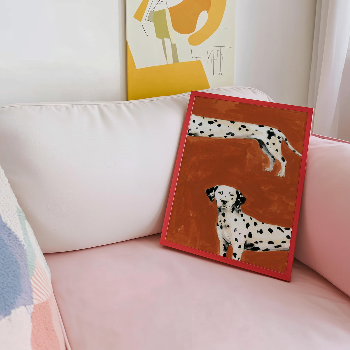 Cropped Dalmatians print shown in a red frame leaning on a blush pink sofa