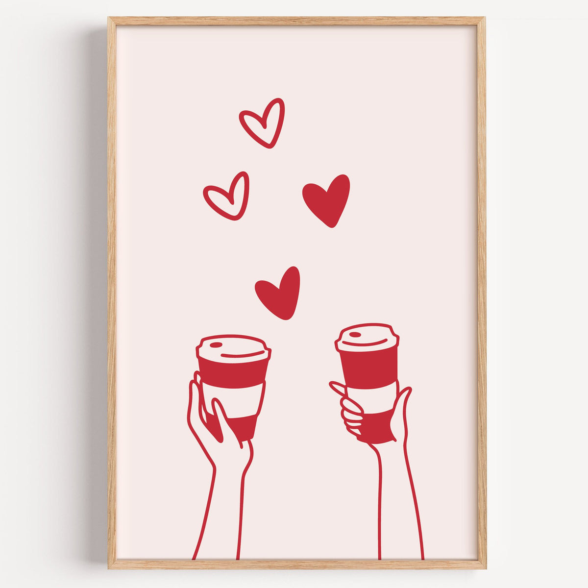 Two hands coffee cups and hearts red line print in a light oak frame on a plain white wall