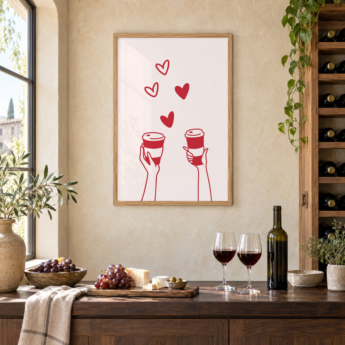 Two hands coffee cups and hearts red line print in an oak frame on a limewashed wall above a wine counter with red wine, cheese and grapes
