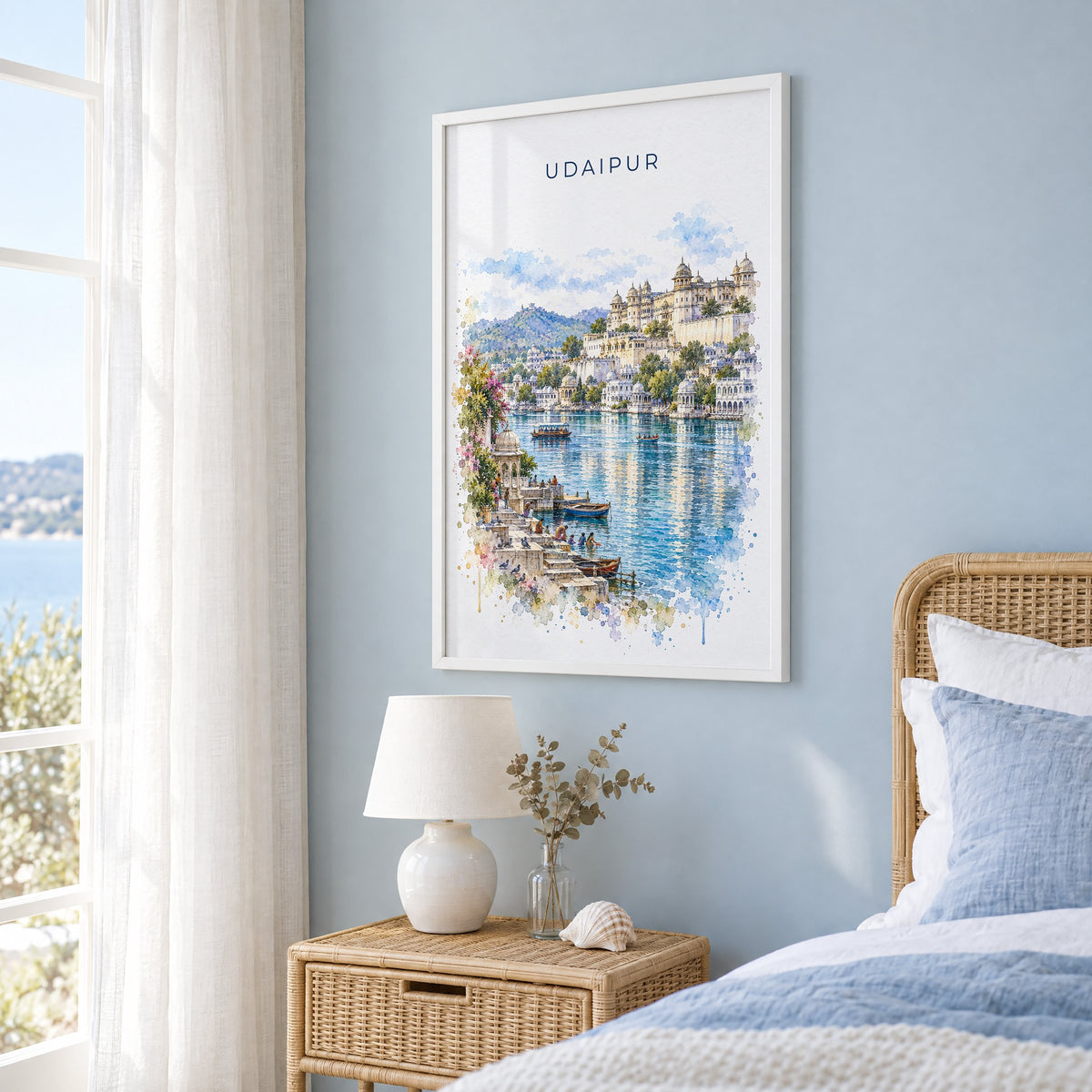 Udaipur watercolor print in a white frame on a pale blue wall beside a rattan bed in a coastal bedroom