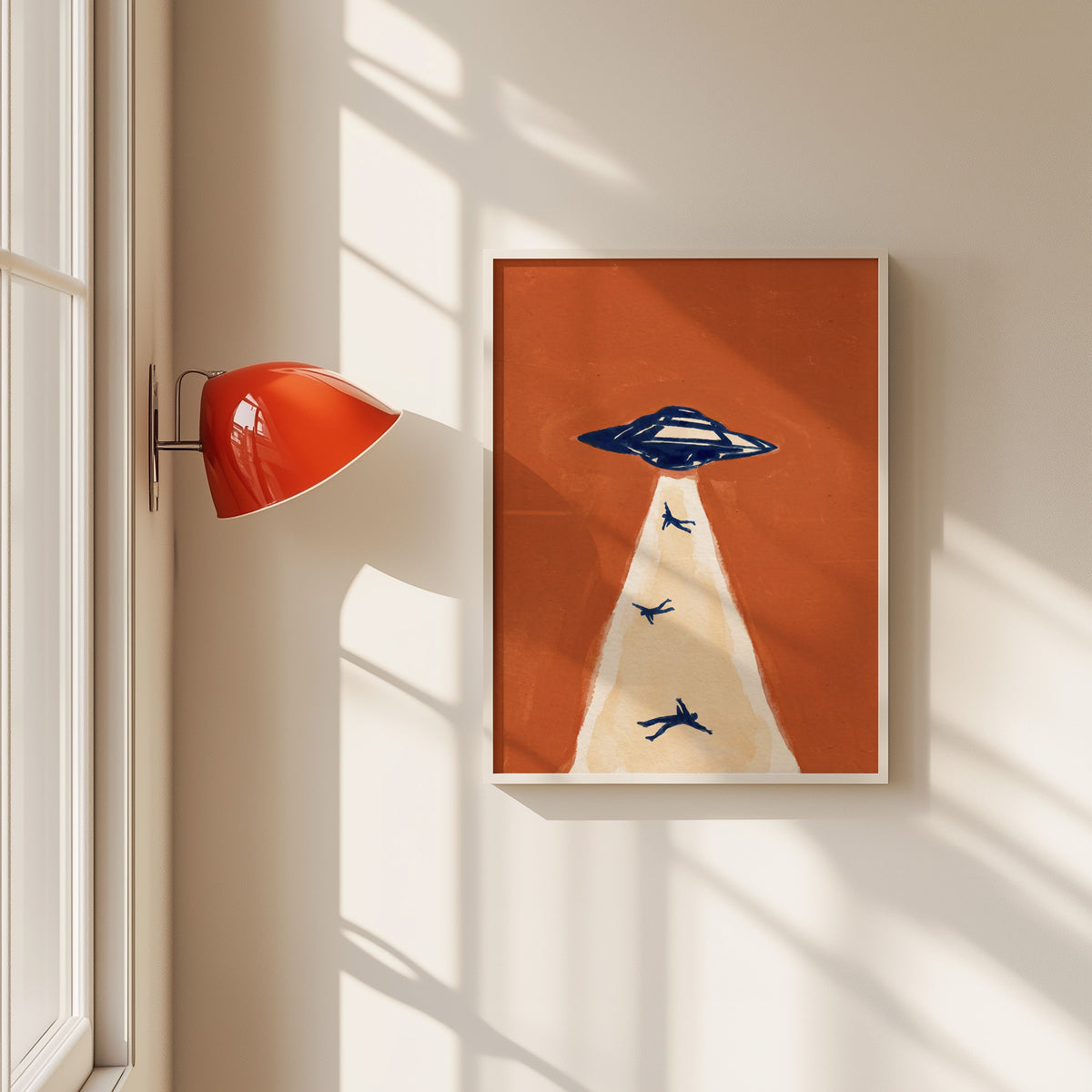 UFO abduction print in a white frame beside a red wall sconce