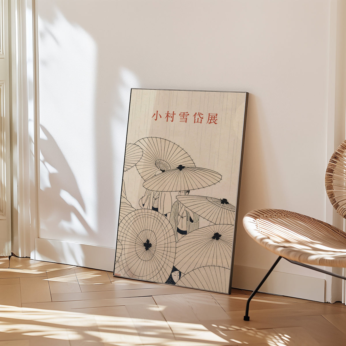 paper umbrellas in the rain line art print in a black frame leaning on a herringbone floor beside a woven rattan chair