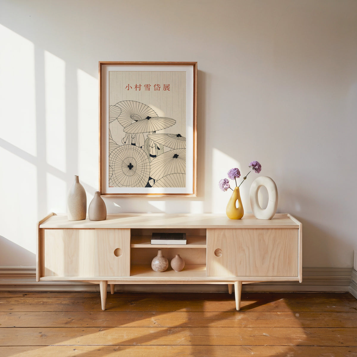 paper umbrellas in the rain line art print shown in a wood frame with a white mat above a pale wood media console