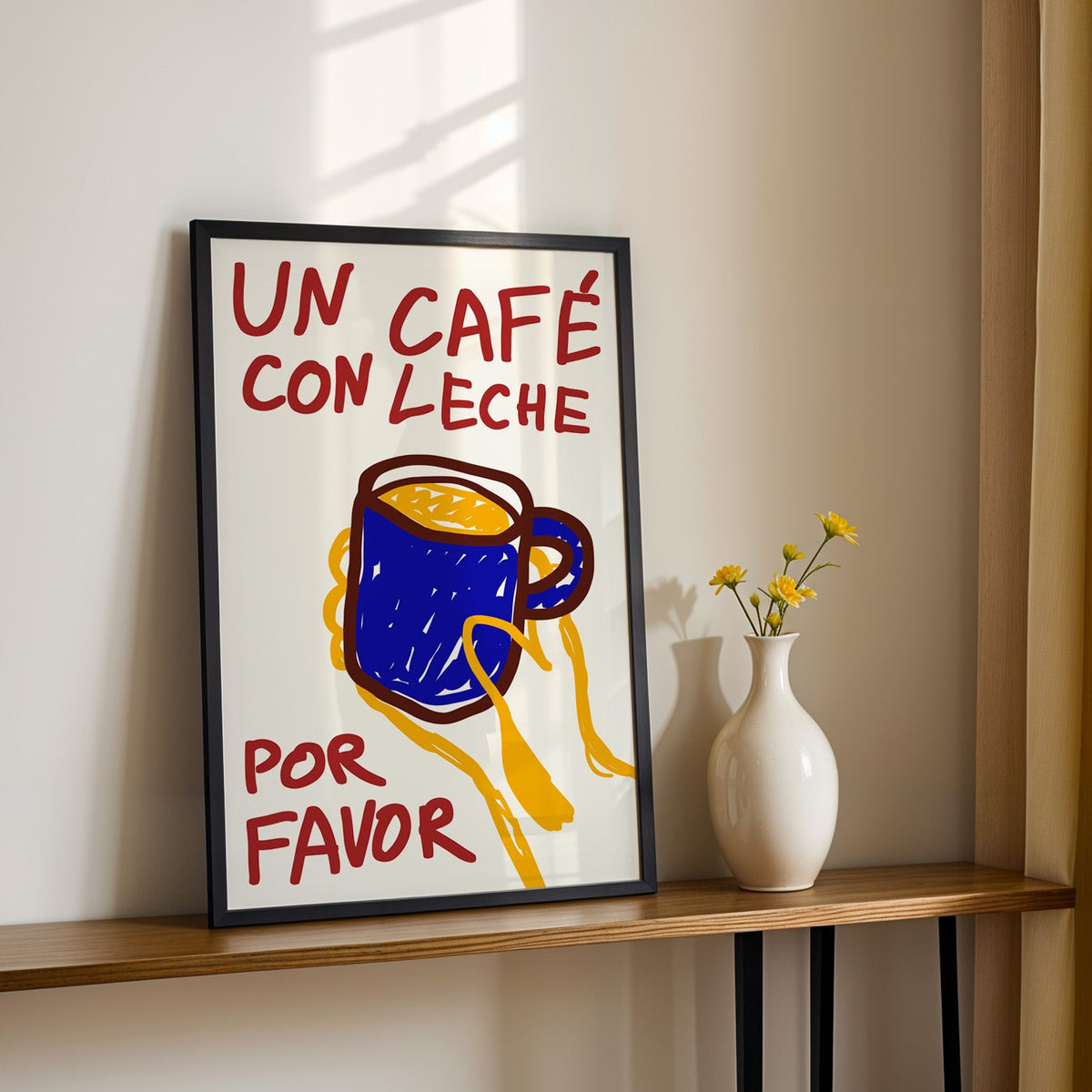 Un cafe con leche print in a black frame on a console table with yellow daisies