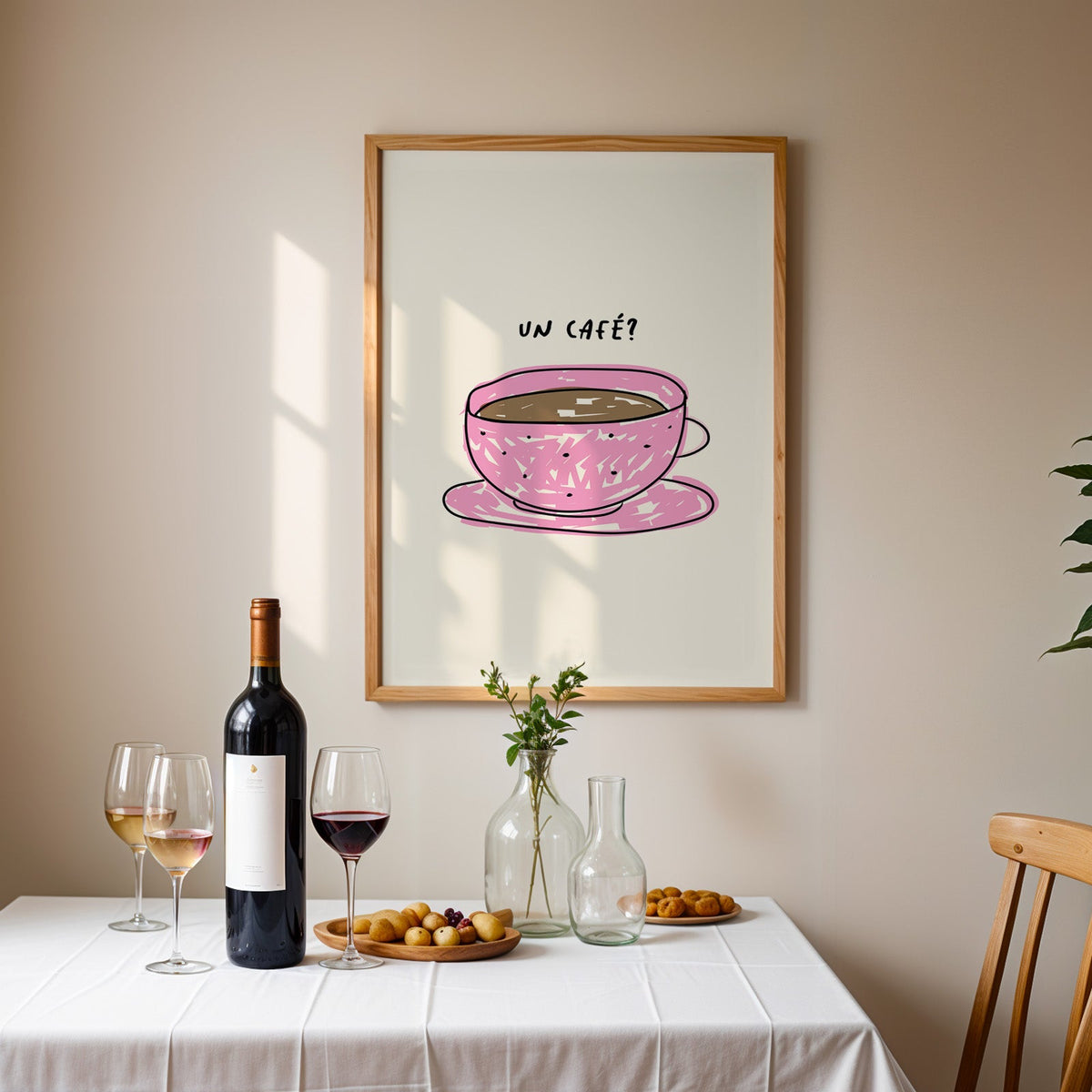Un cafe pink cup print in an oak frame above a table laid with red wine and glasses