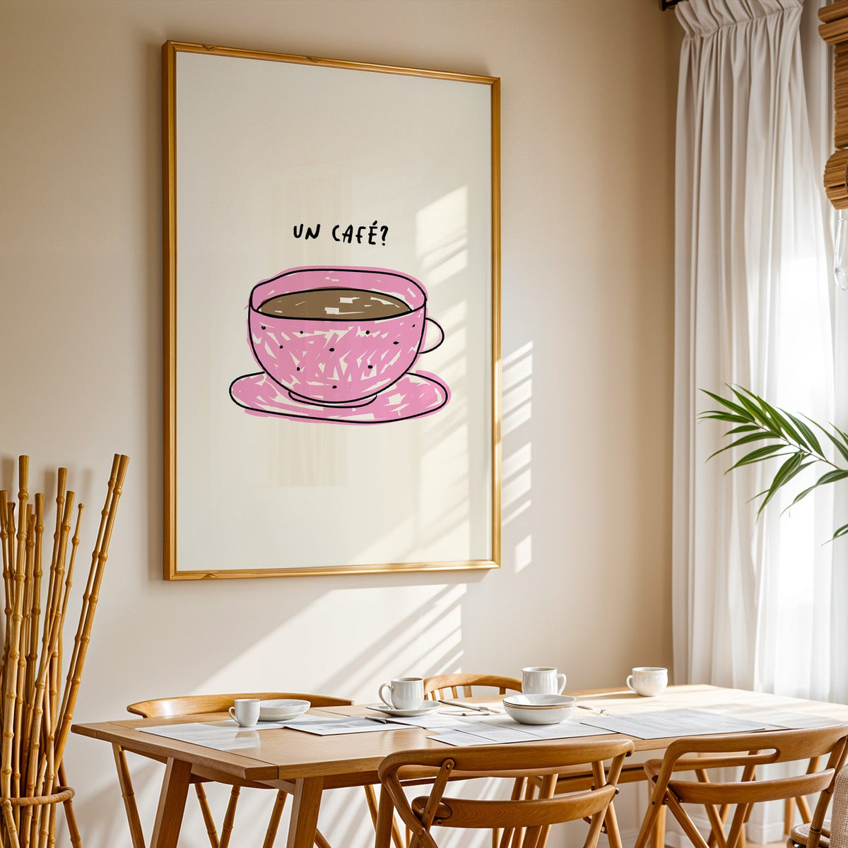 Un cafe pink cup print in a gold frame above a sunlit breakfast table