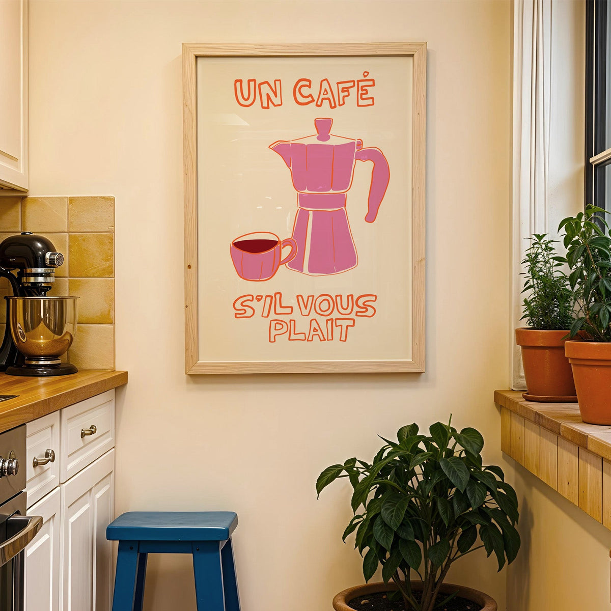 Un cafe pink moka pot print in a wood frame on a yellow tiled kitchen wall