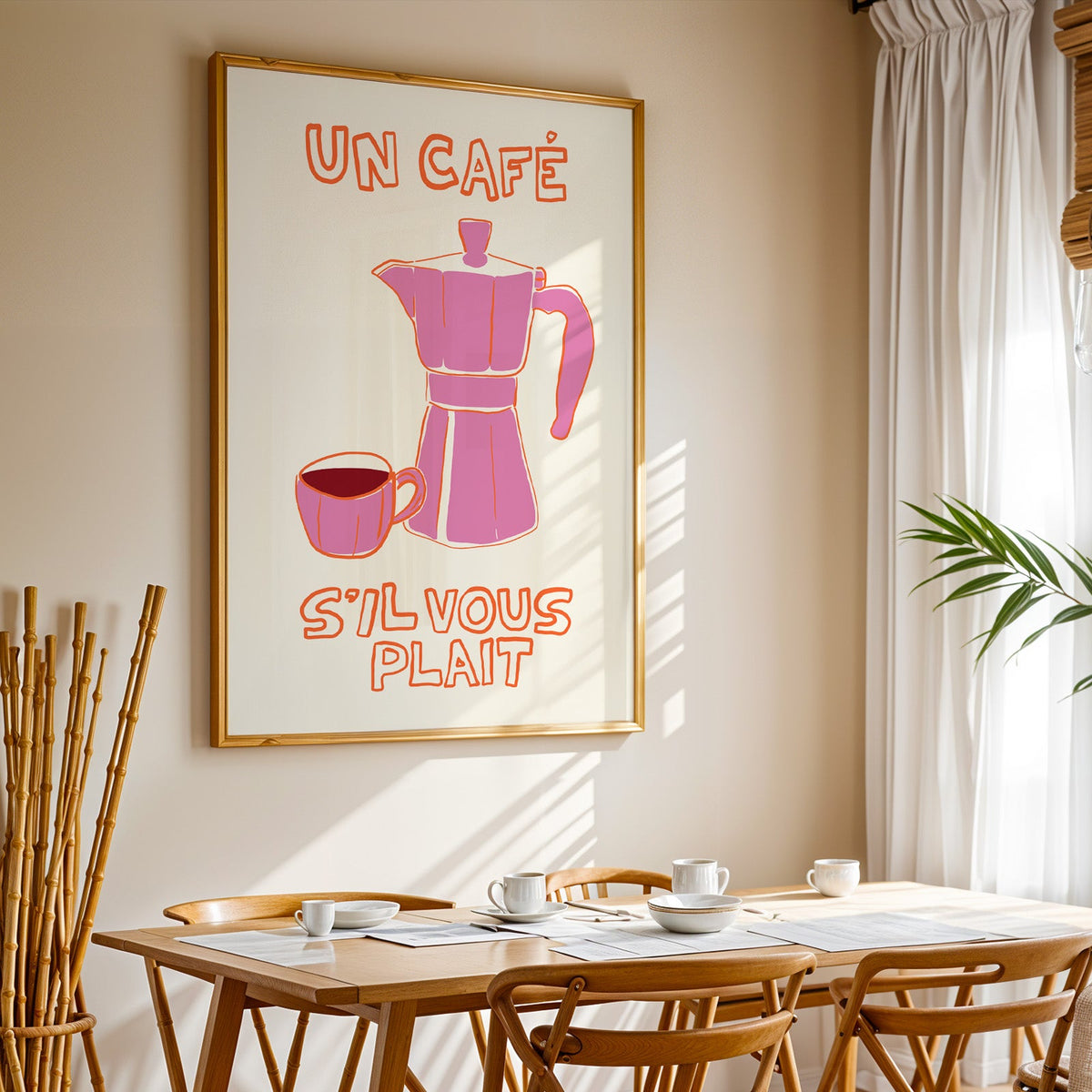 Un cafe pink moka pot print in a gold frame above a sunlit breakfast table