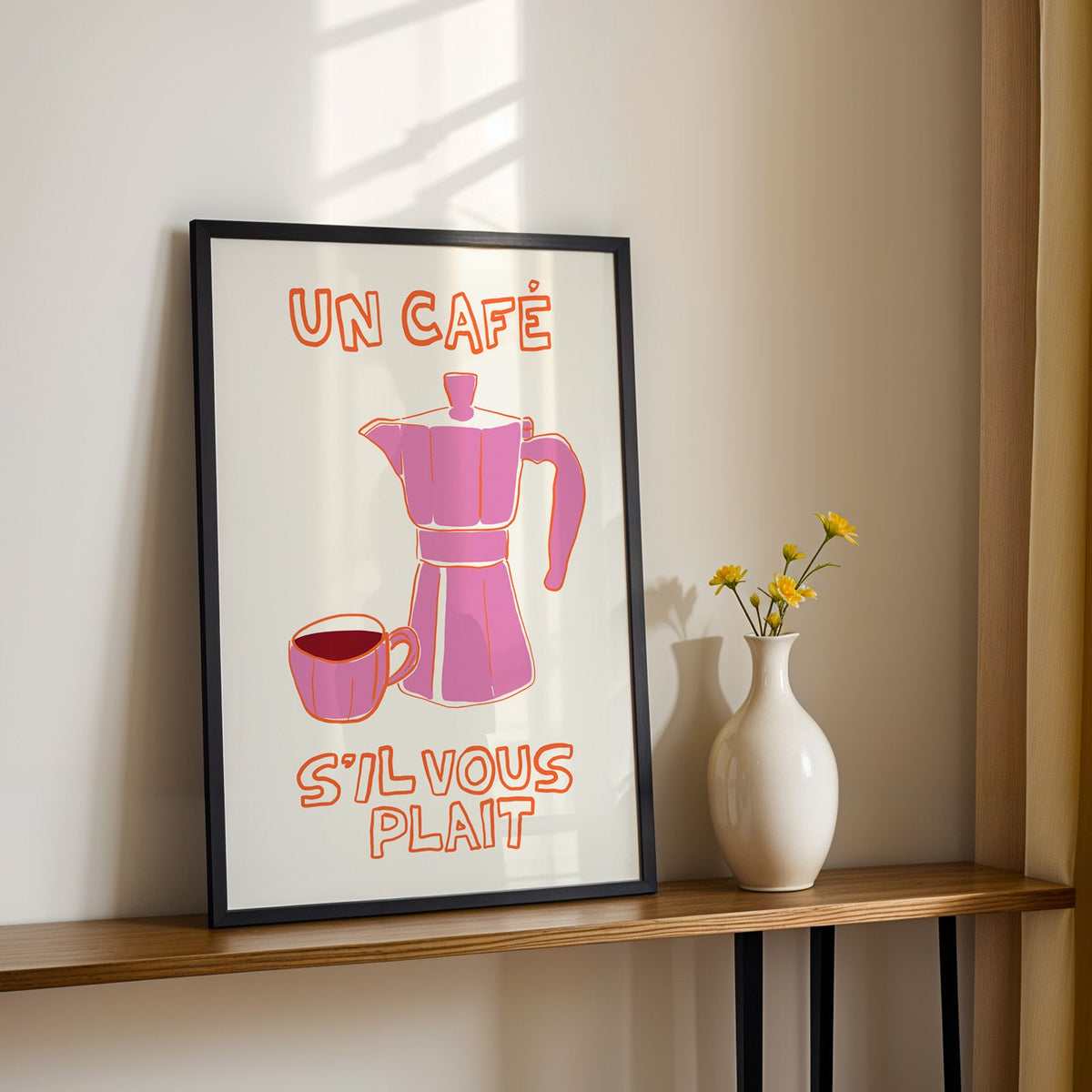 Un cafe pink moka pot print in a black frame on a console table with daisies