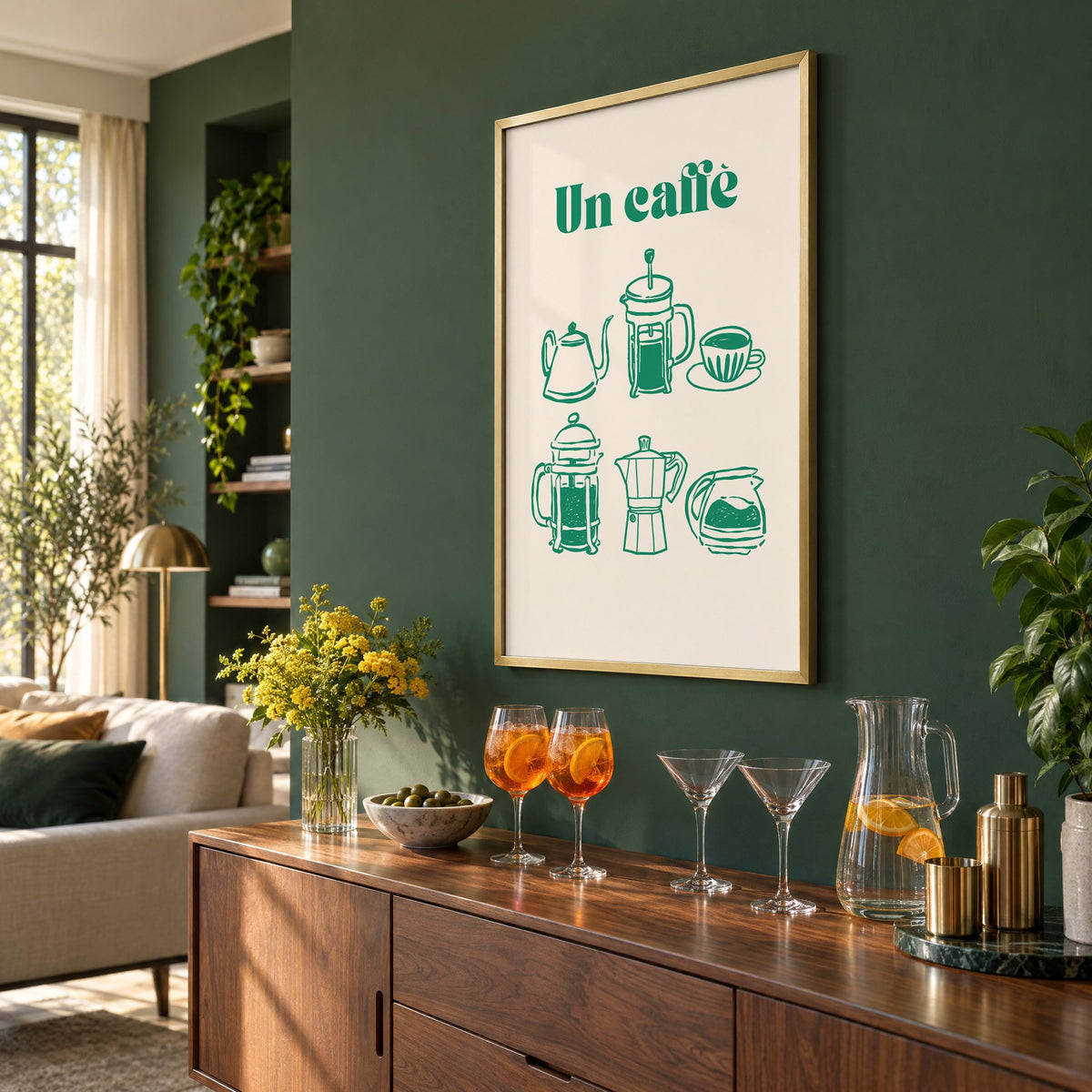 Un caffè green coffee makers print in a brass frame on a bottle green wall above a sideboard with spritz and martini glasses, seen at an angle