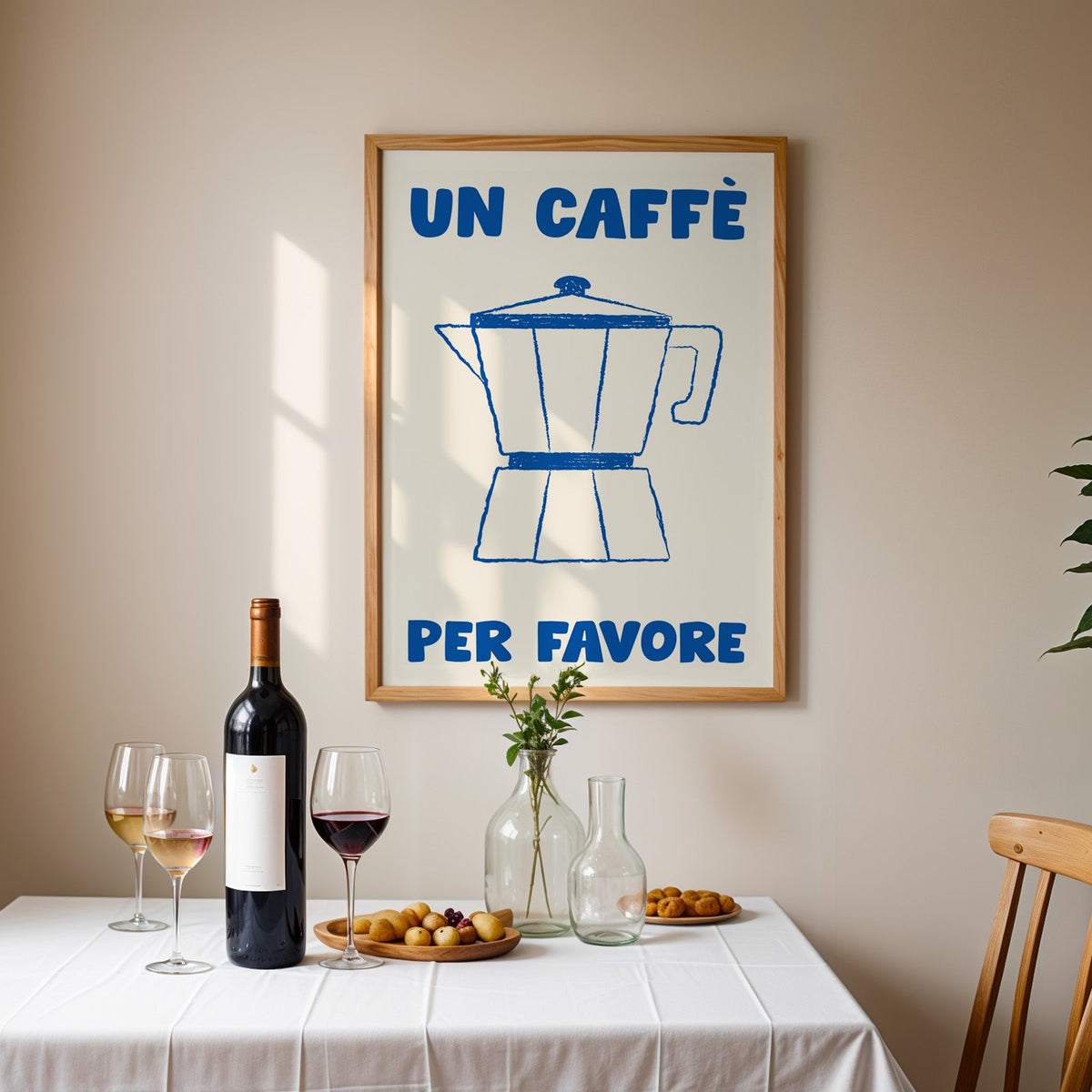 Un caffe per favore moka pot print in an oak frame above a table laid with red wine