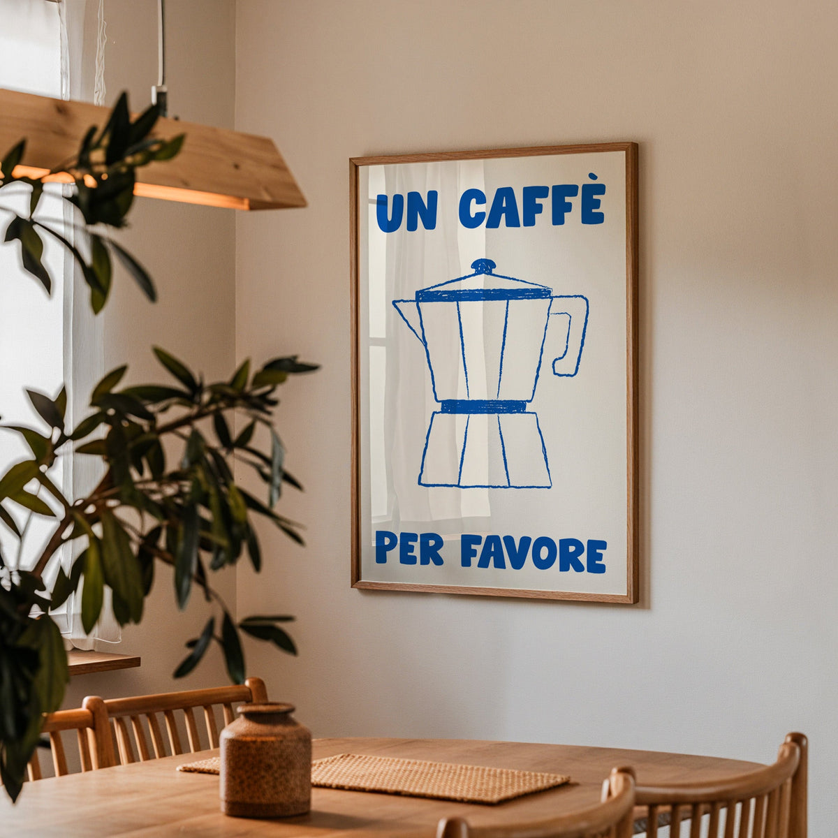 Un caffe per favore moka pot print in a walnut frame above a table by an olive tree