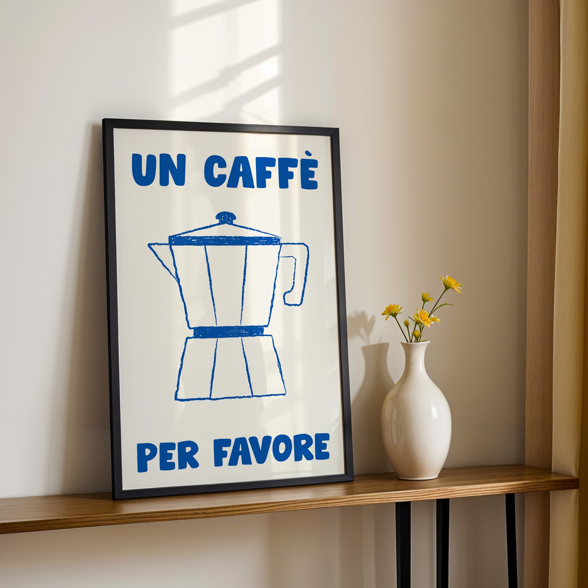 Un caffe per favore moka pot print in a black frame on a console table with daisies